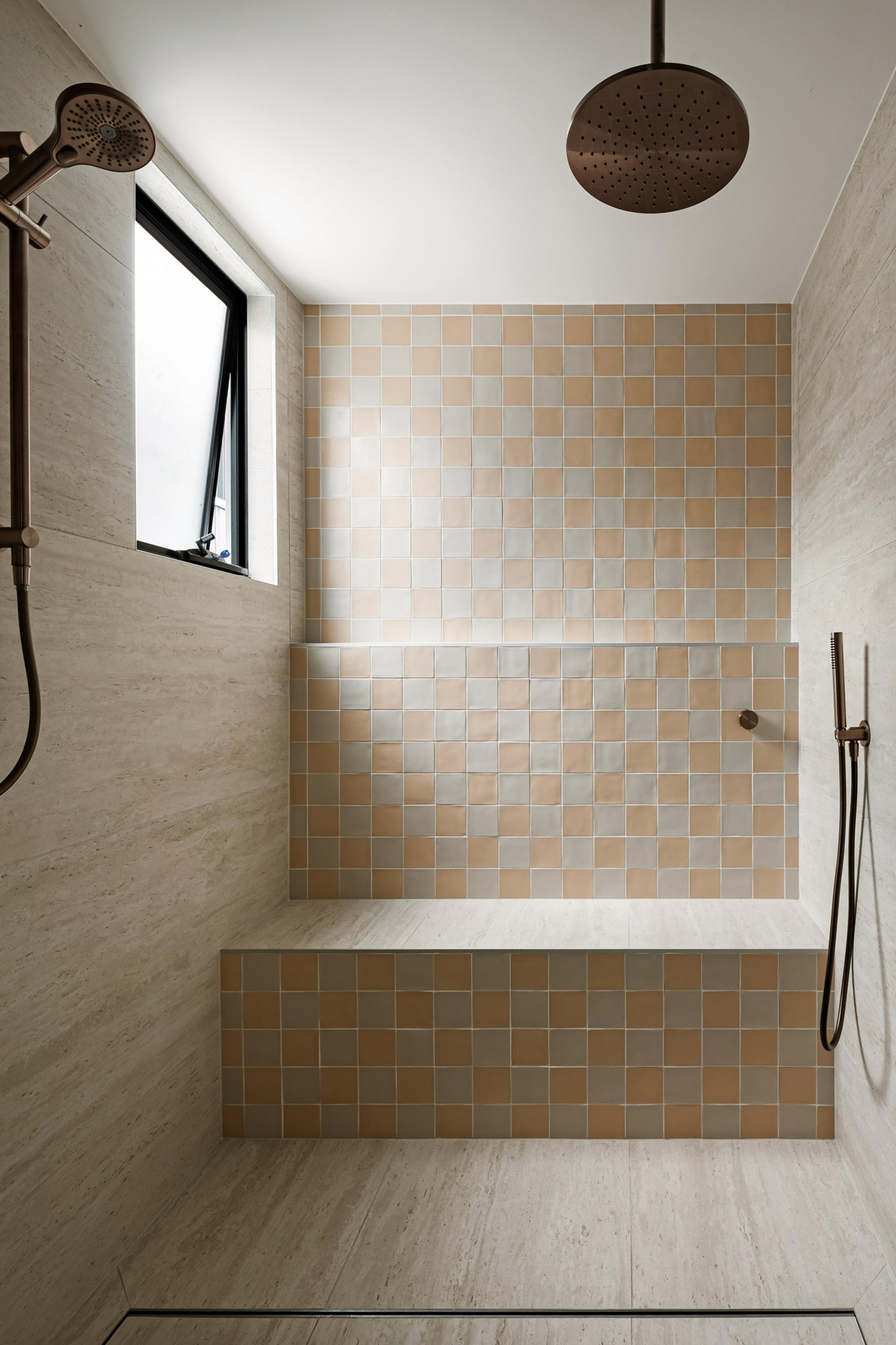 Shower with peach and grey chequered tiles and built in bench