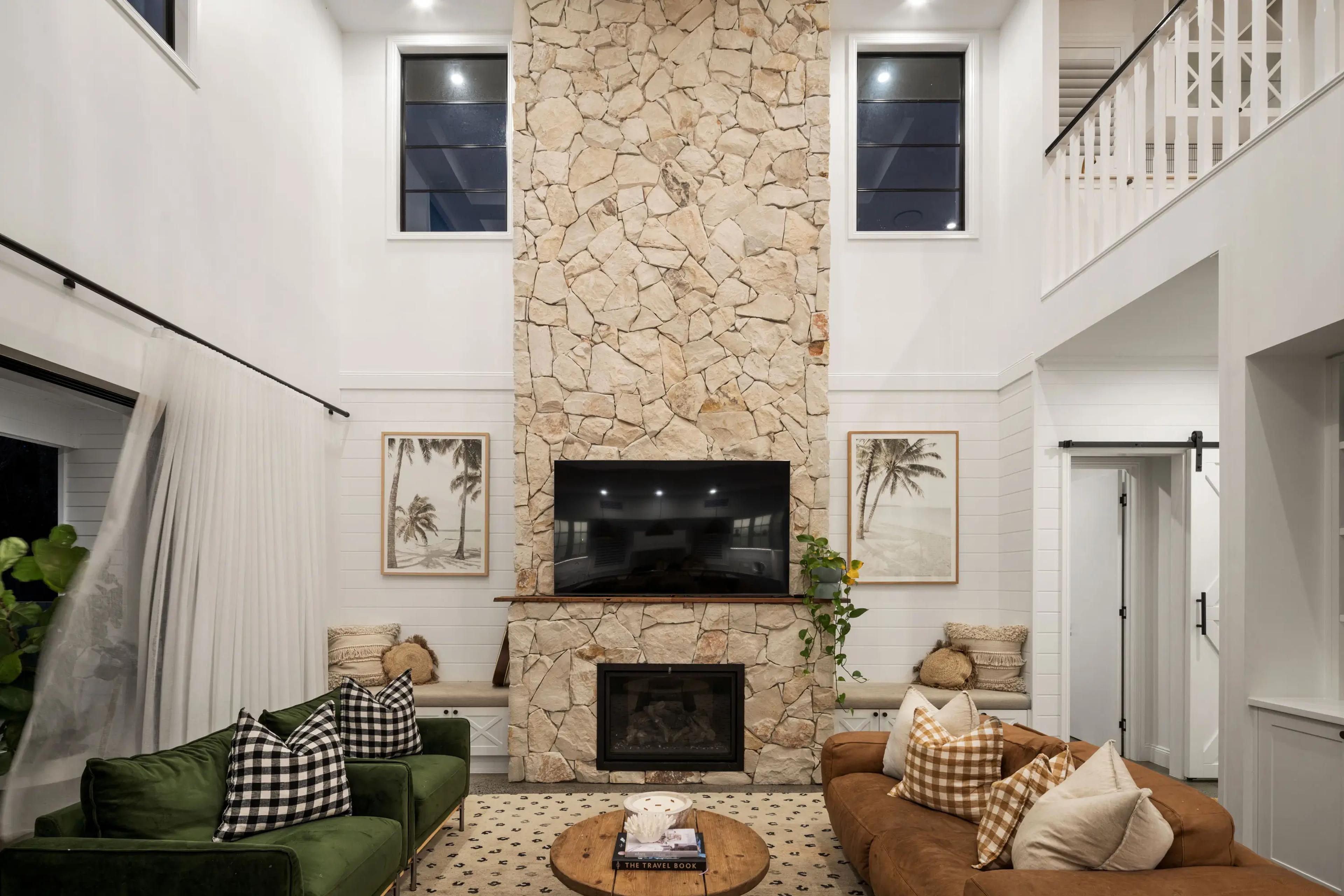 Living room with floor to ceiling stone fireplace and mounted television