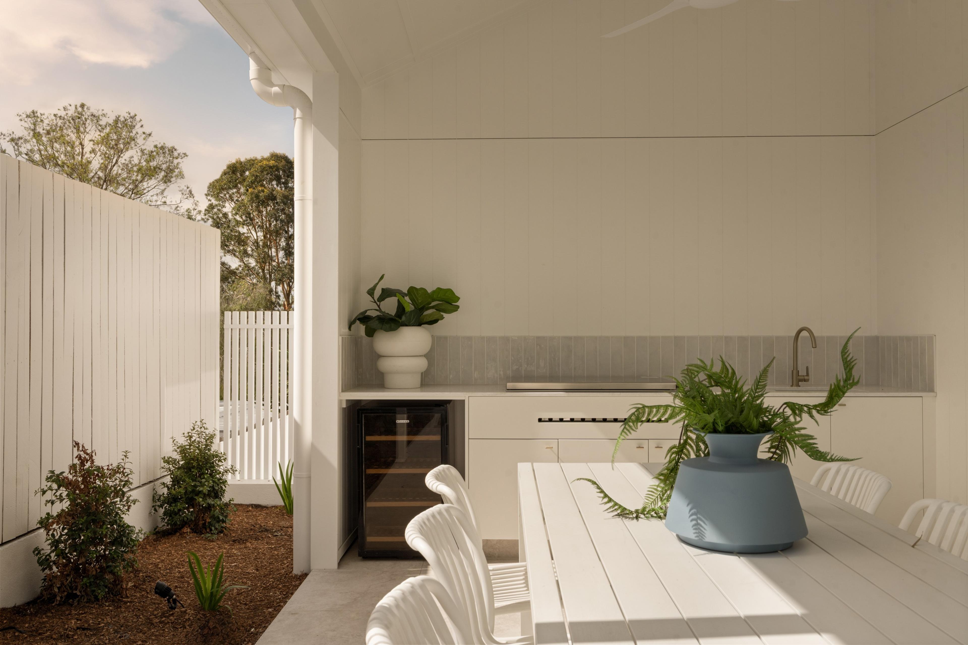 Covered outdoor kitchen with dining table and greenery
