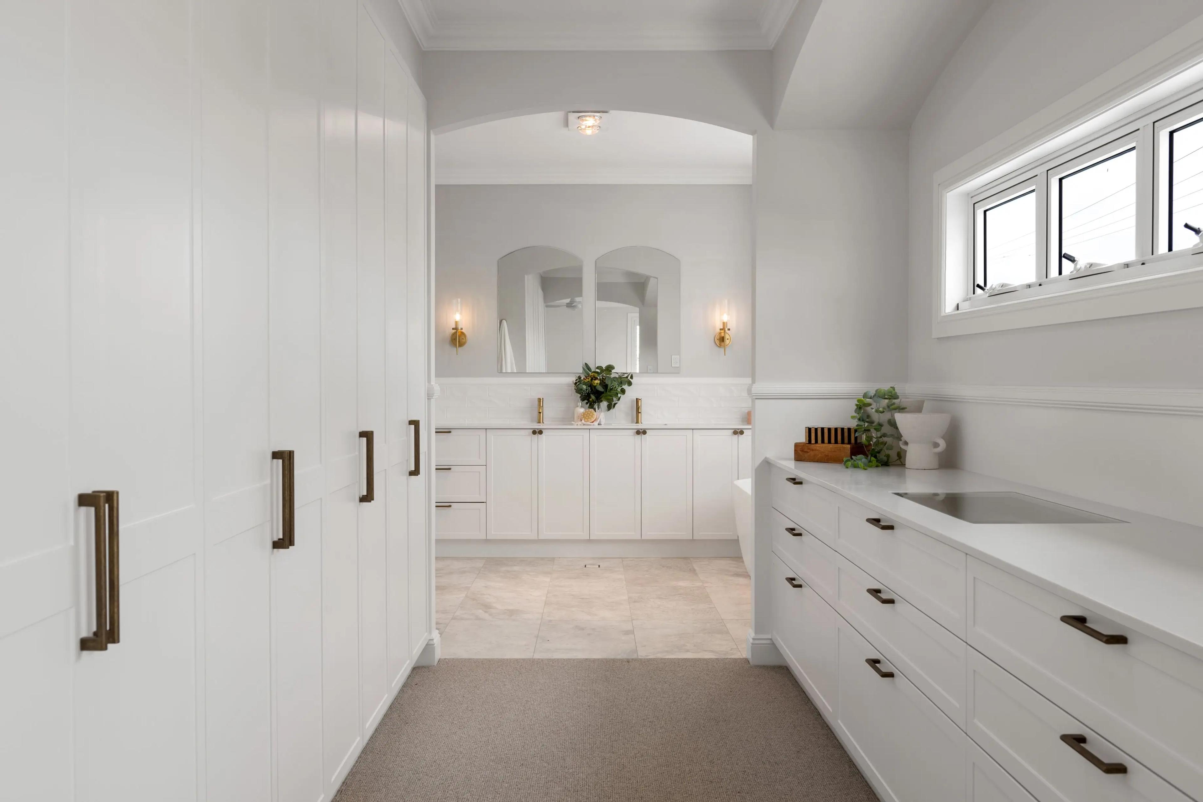 Ensuite with white cabinetry, arched mirrors and floor tiles
