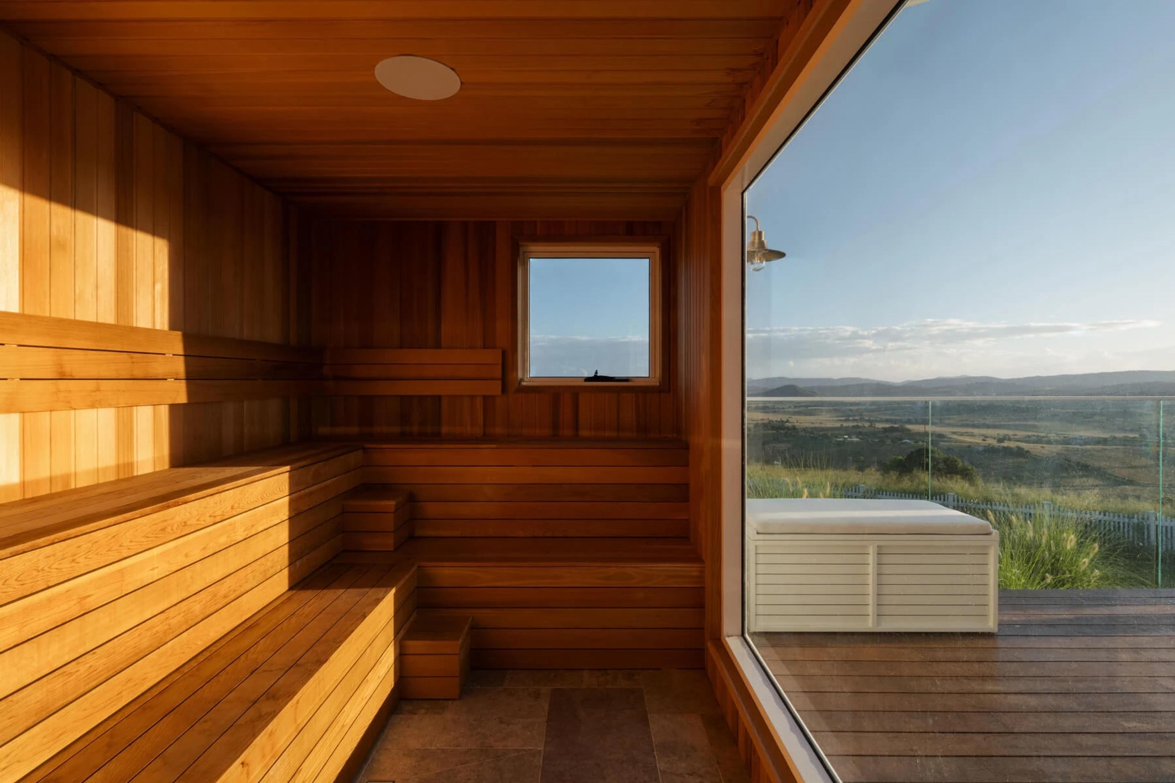 Timber sauna interior with large window framing rural view
