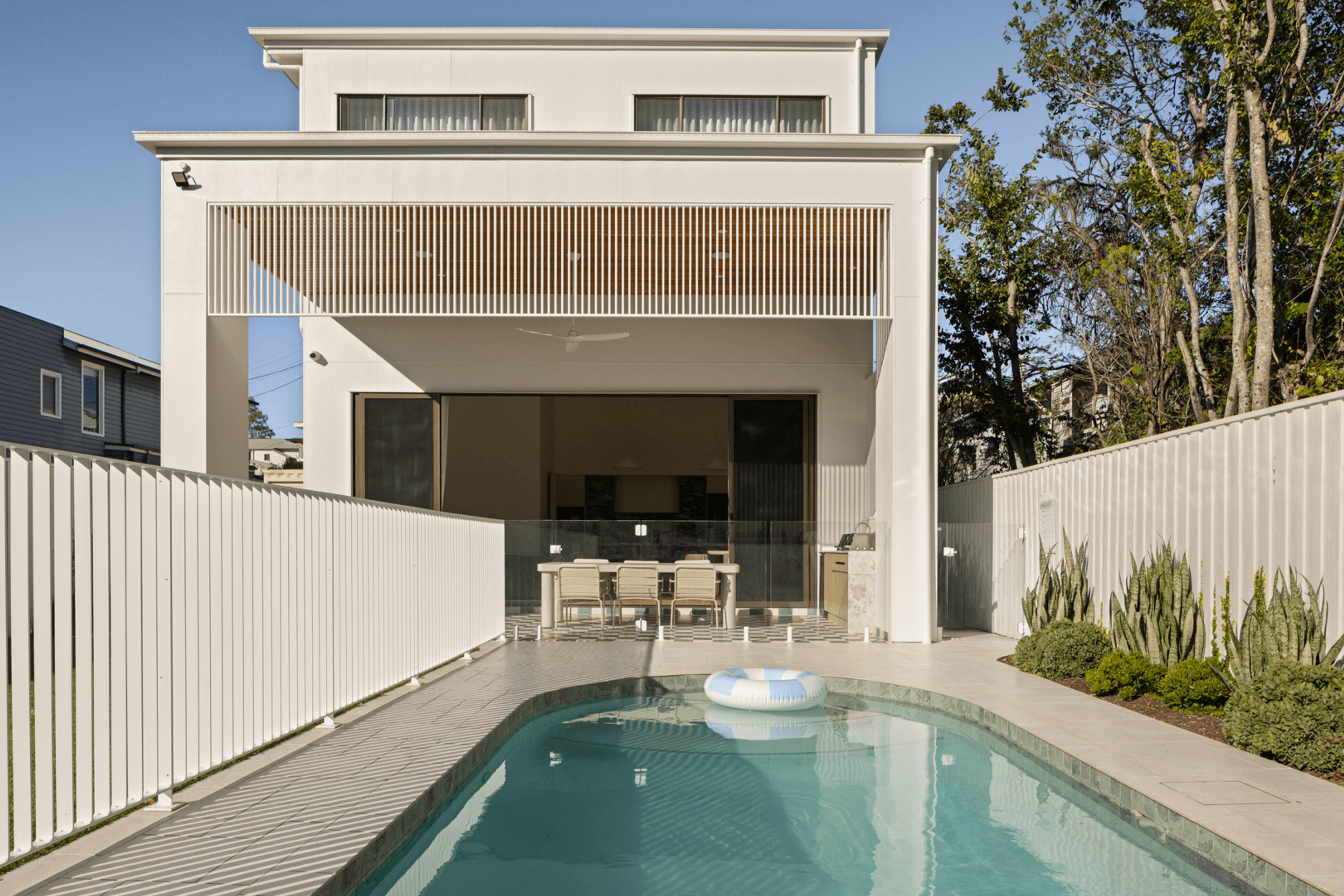 Backyard pool and alfresco below white battened balcony