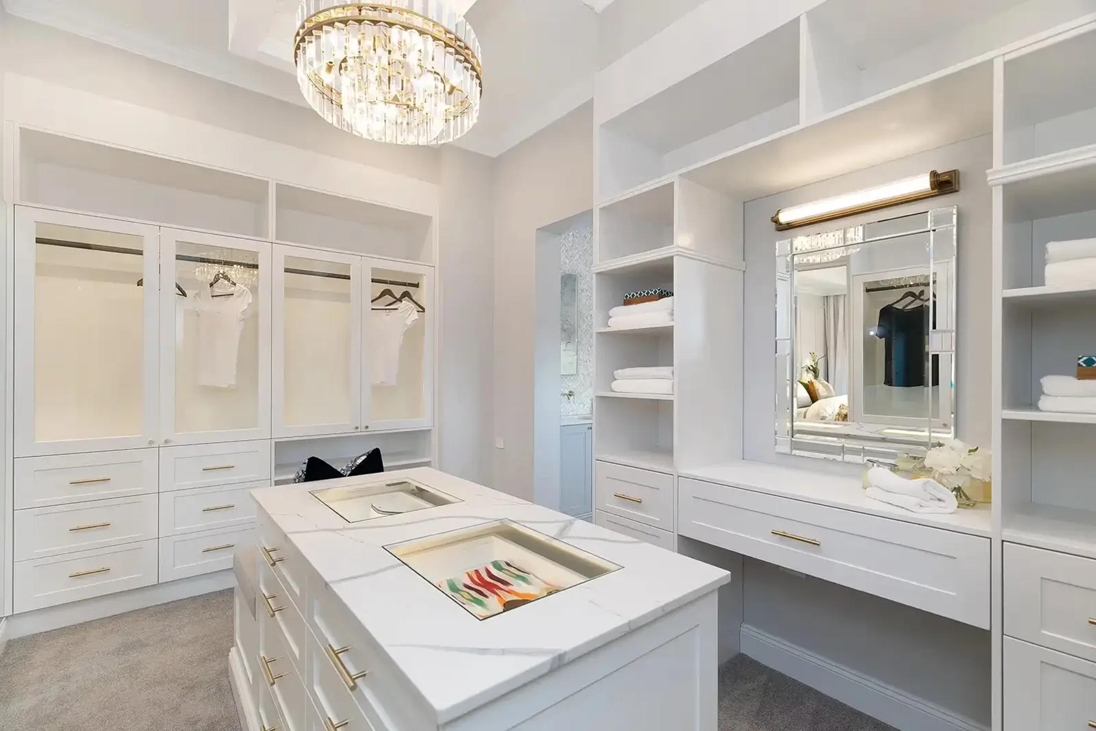 Walk in wardrobe with marble island, mirror and dressing station