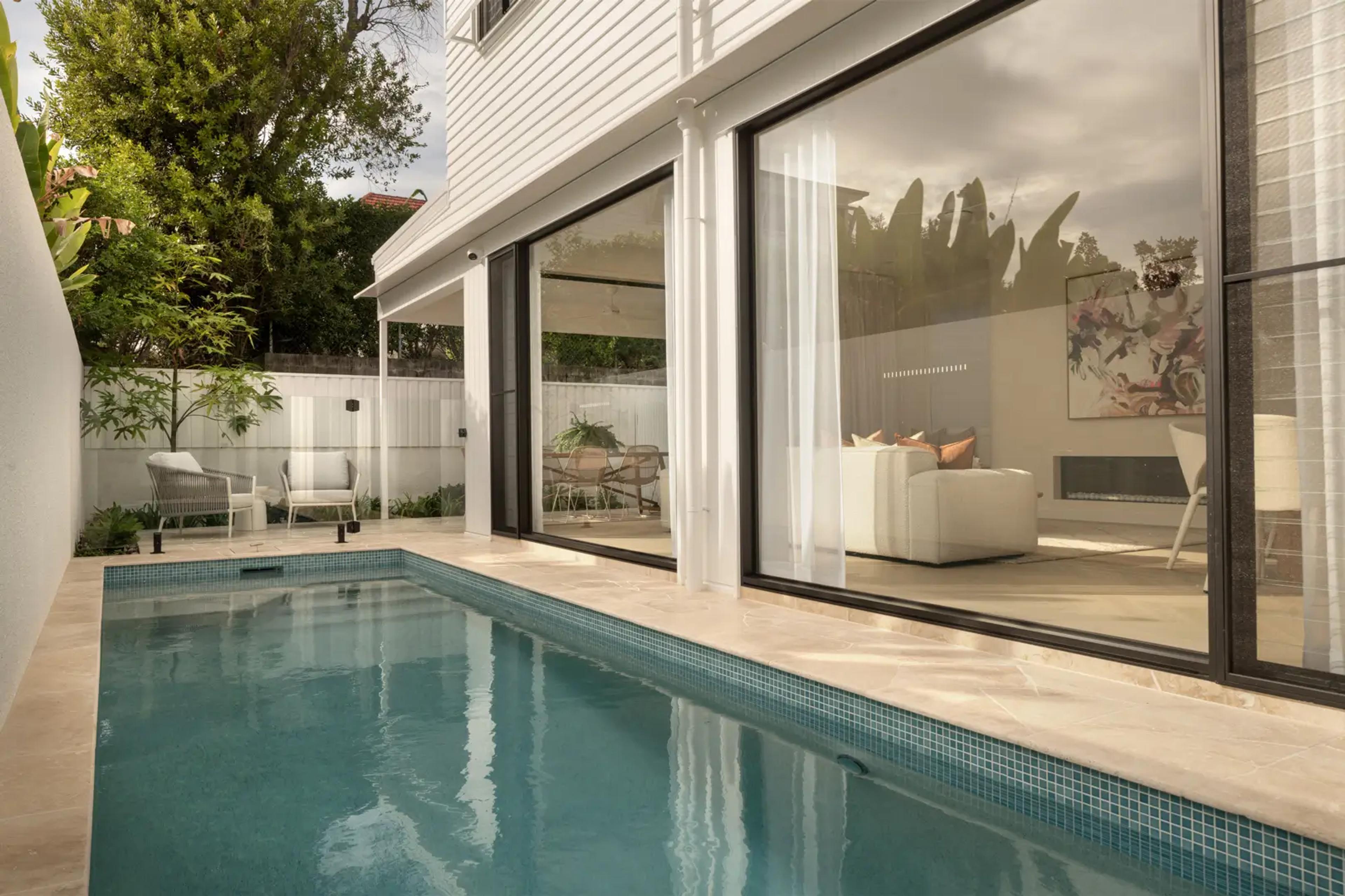 Courtyard pool beside home with large glass doors