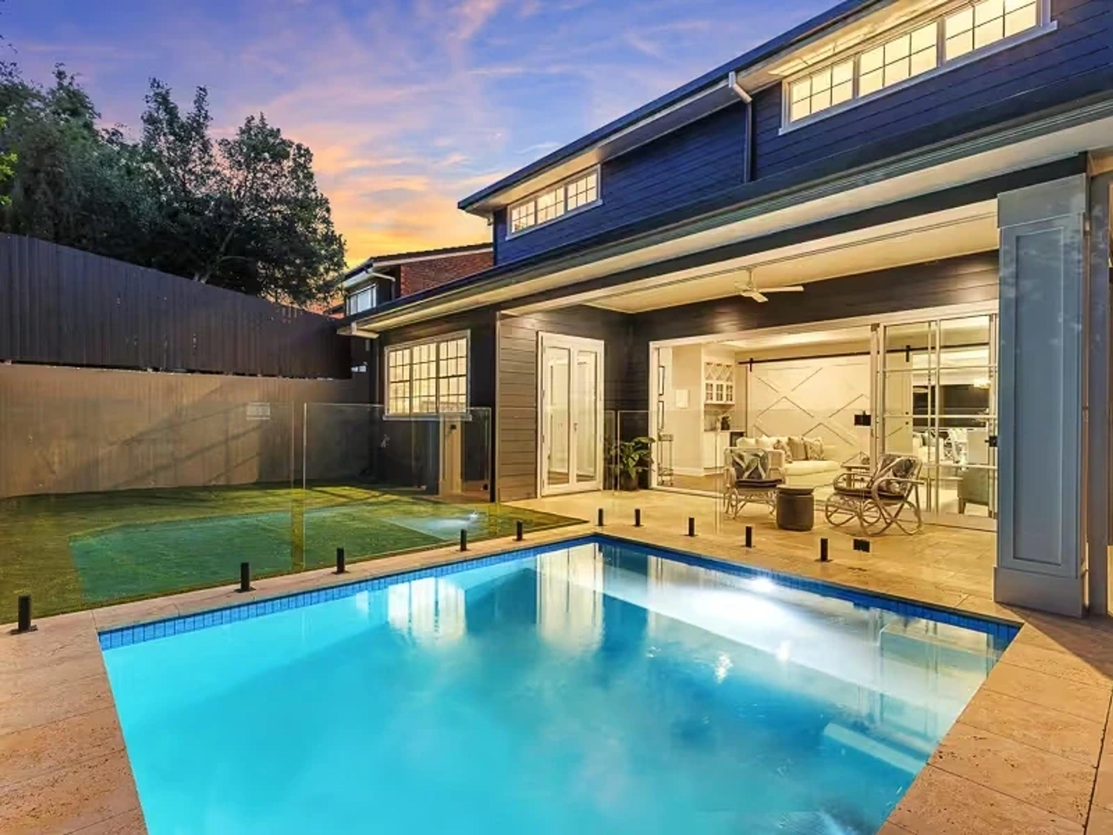 Backyard swimming pool and rear facade at dusk