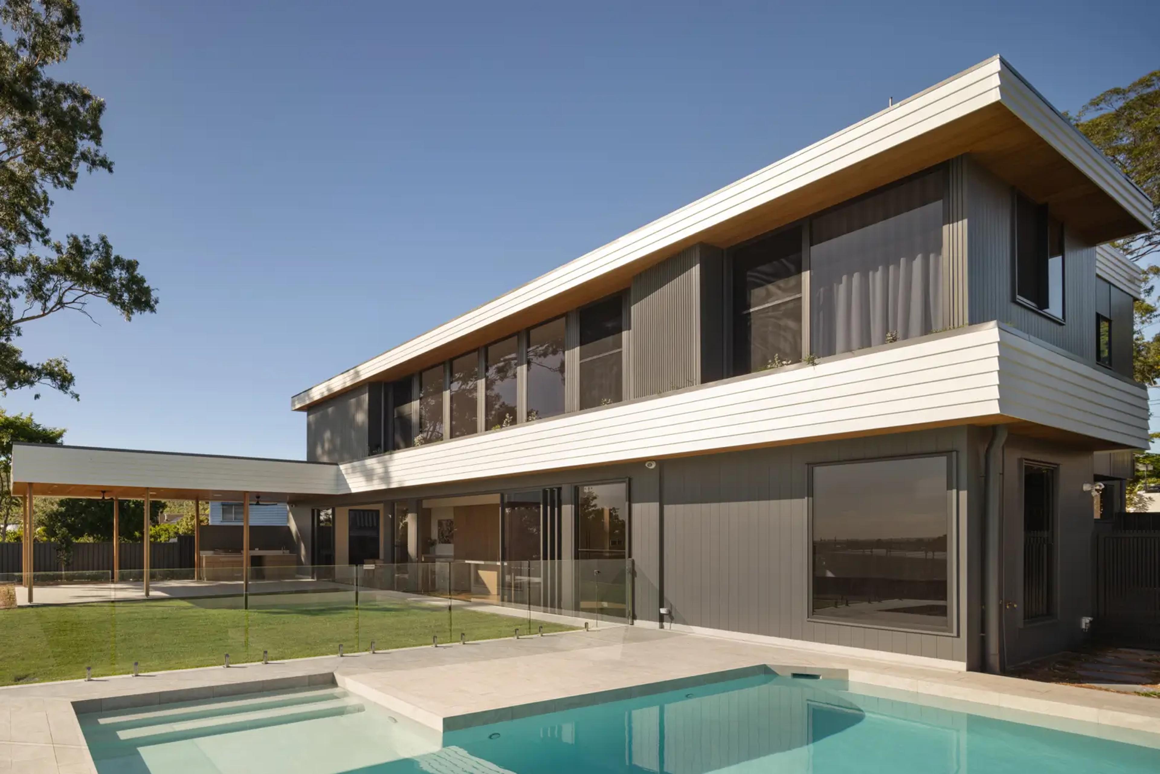 Rear elevation of two storey home with pool and lawn