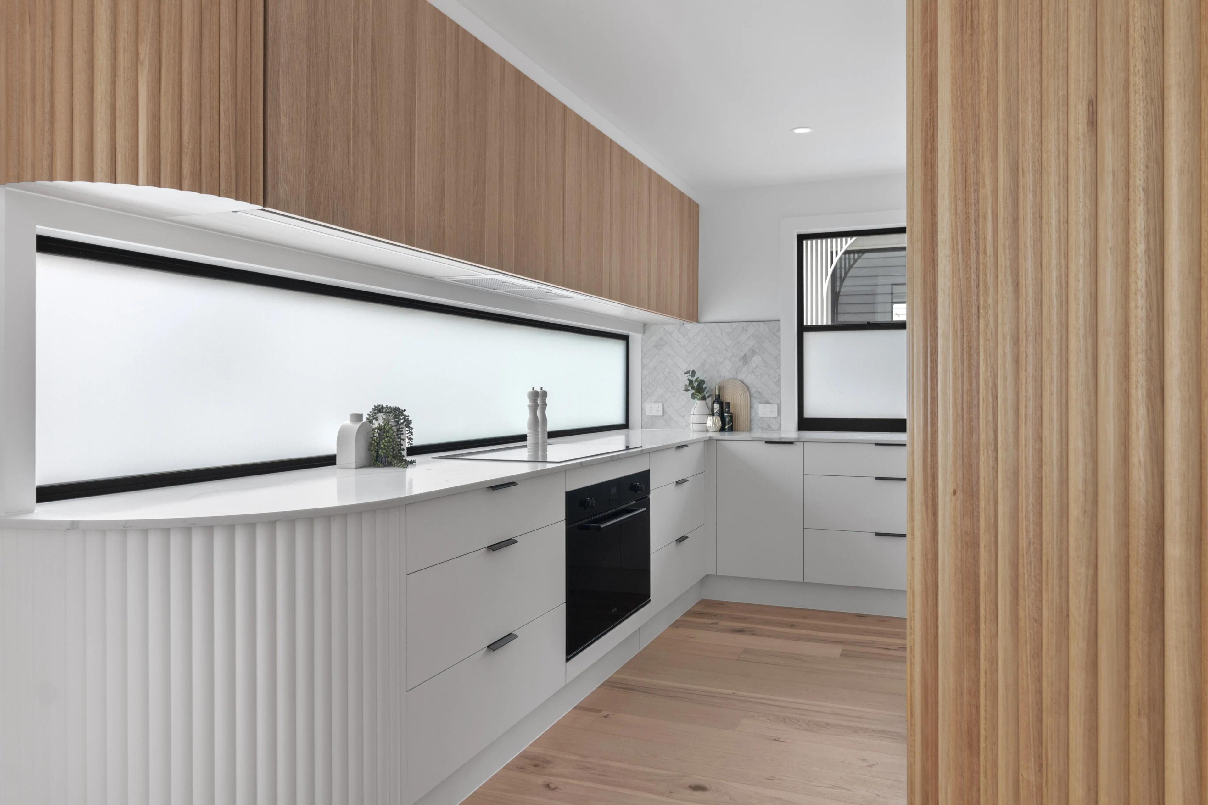 Kitchen with timber cabinetry, white benchtop and window splashback