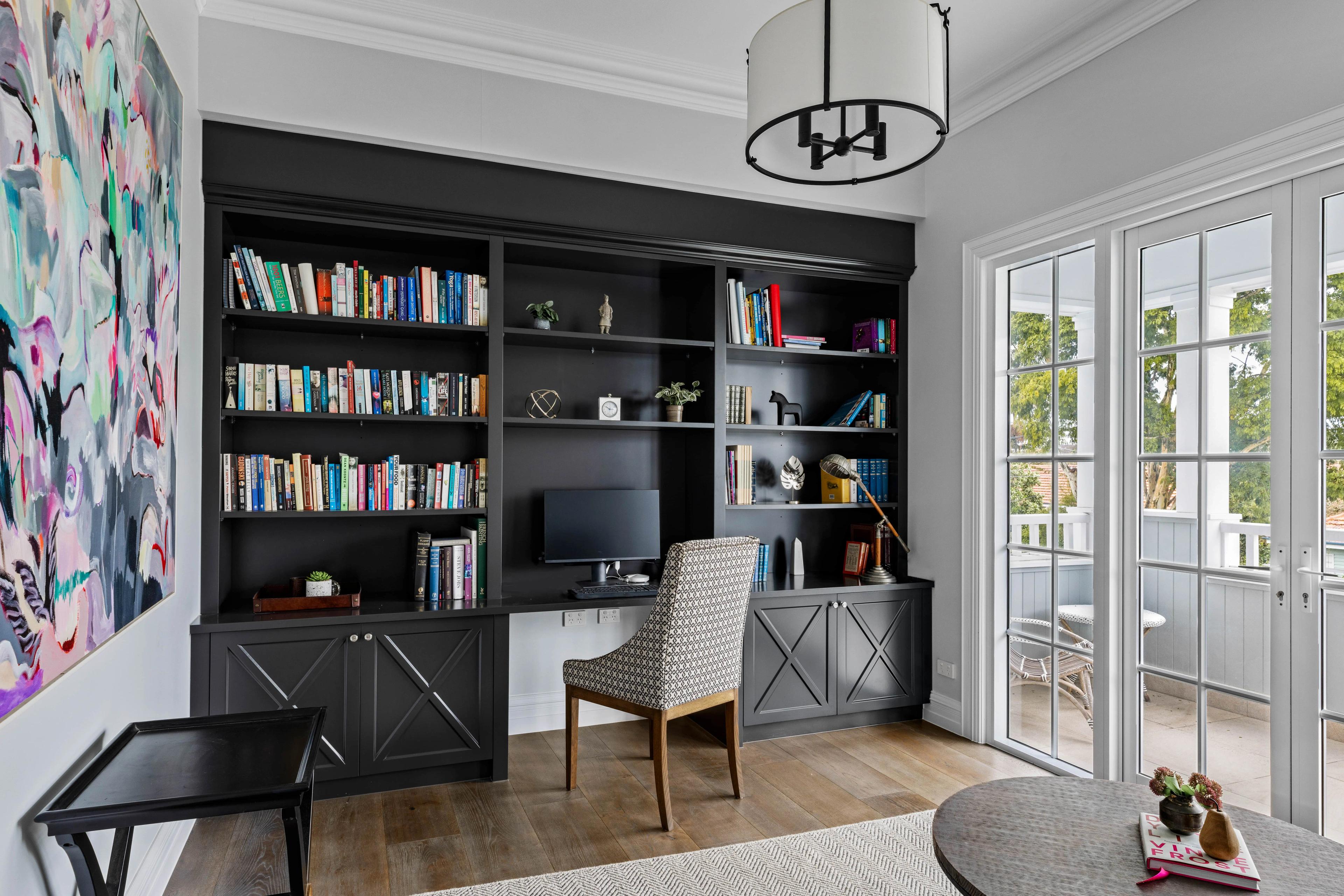 Home study with black built in bookshelves, desk and French doors