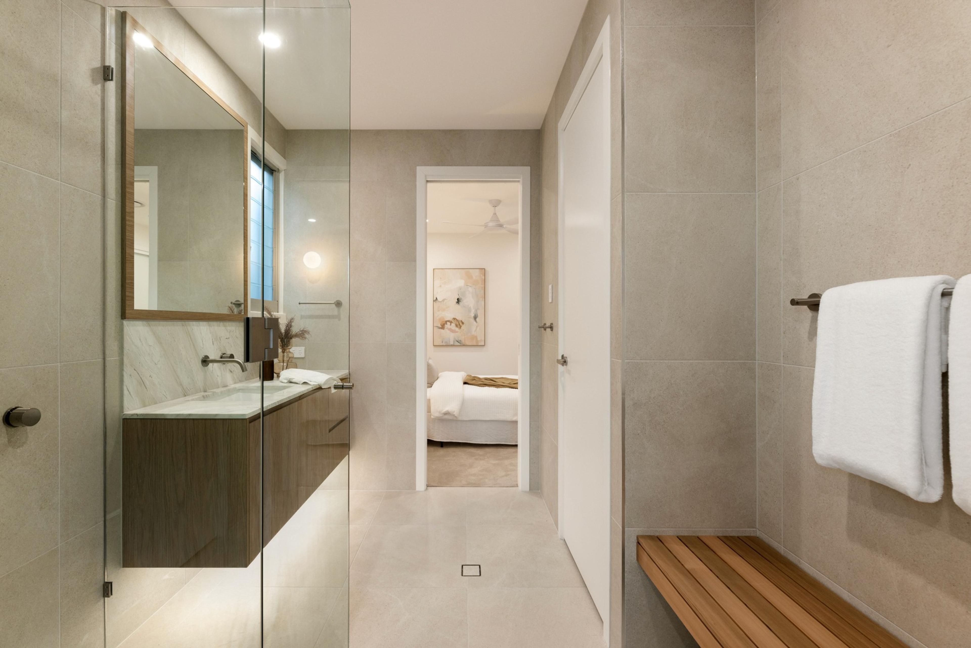 Ensuite bathroom with glass shower and timber bench