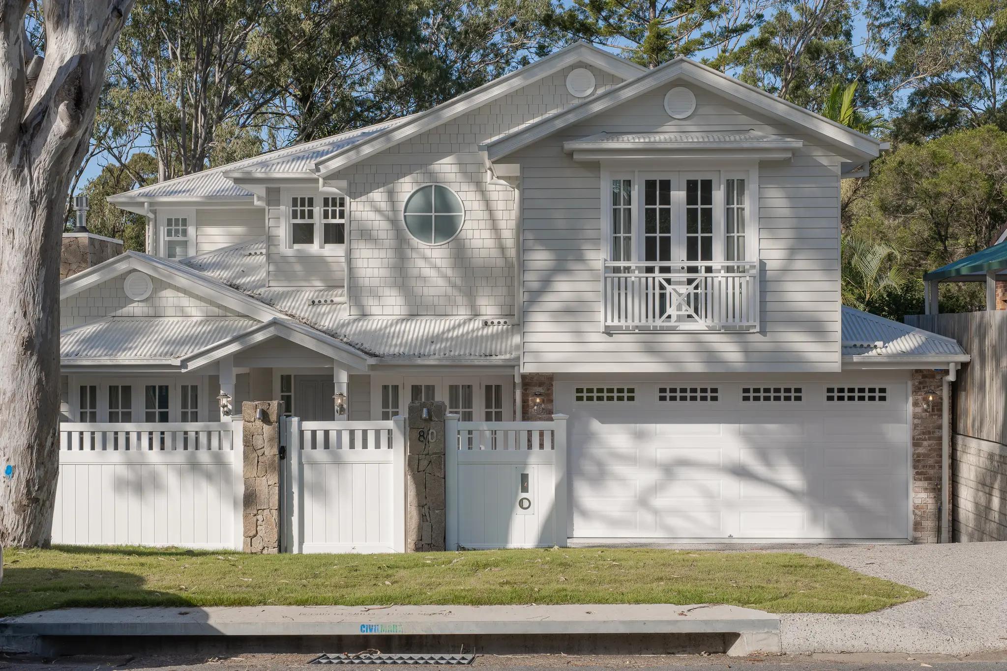 White weatherboard two storey Hamptons style home with double garage and street frontage