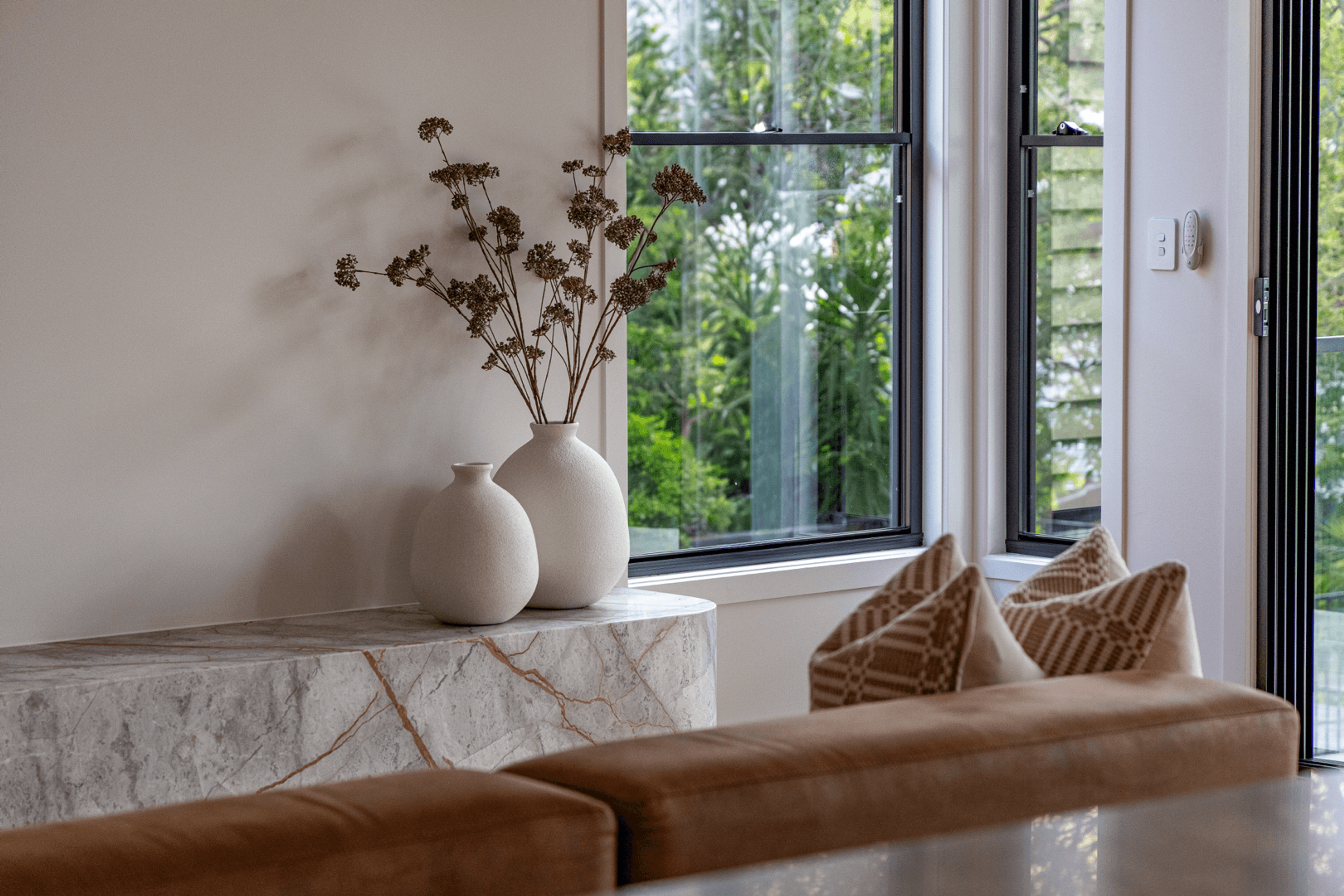 Stone bench with white vases beside a garden window