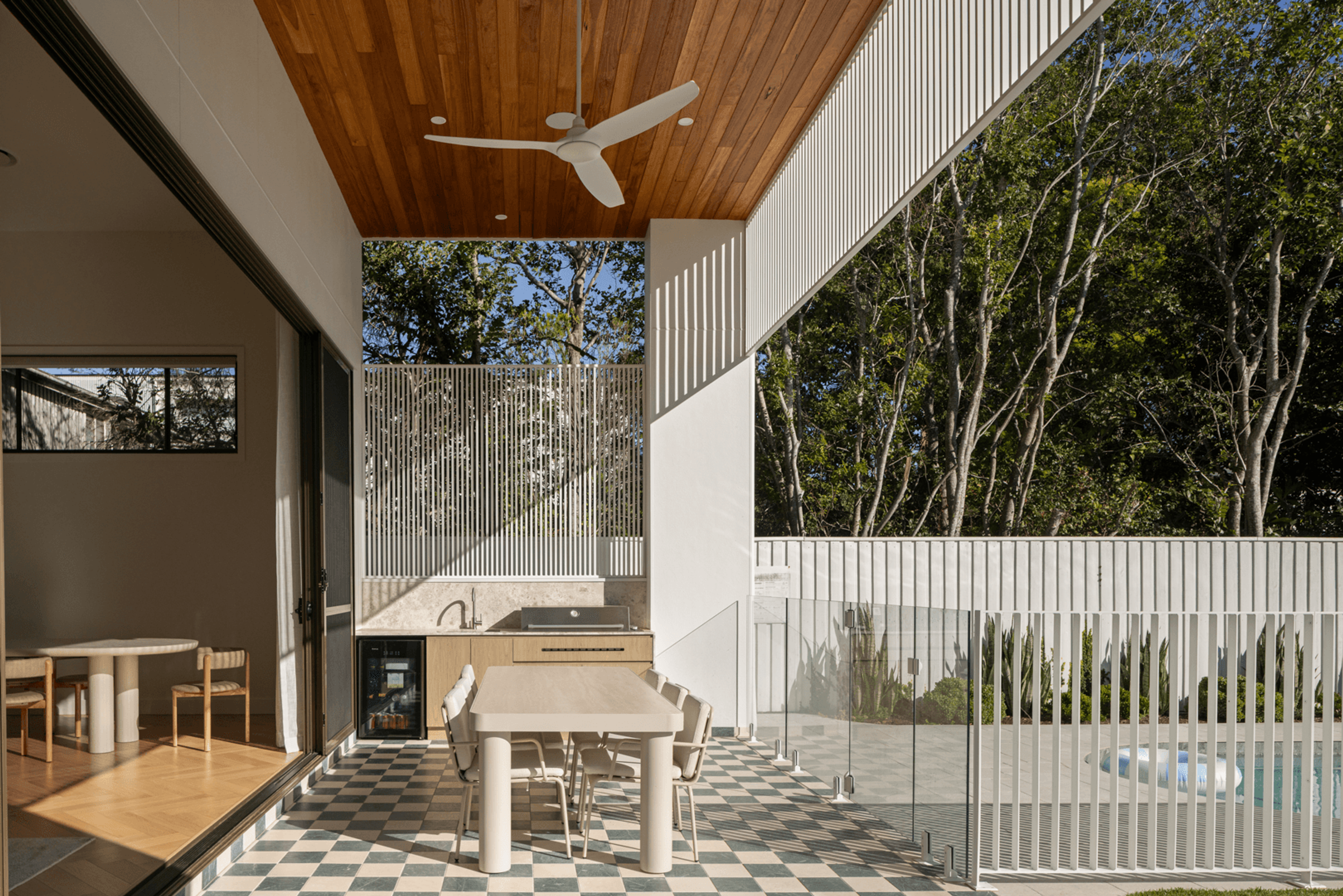 Covered outdoor dining area with timber ceiling and pool