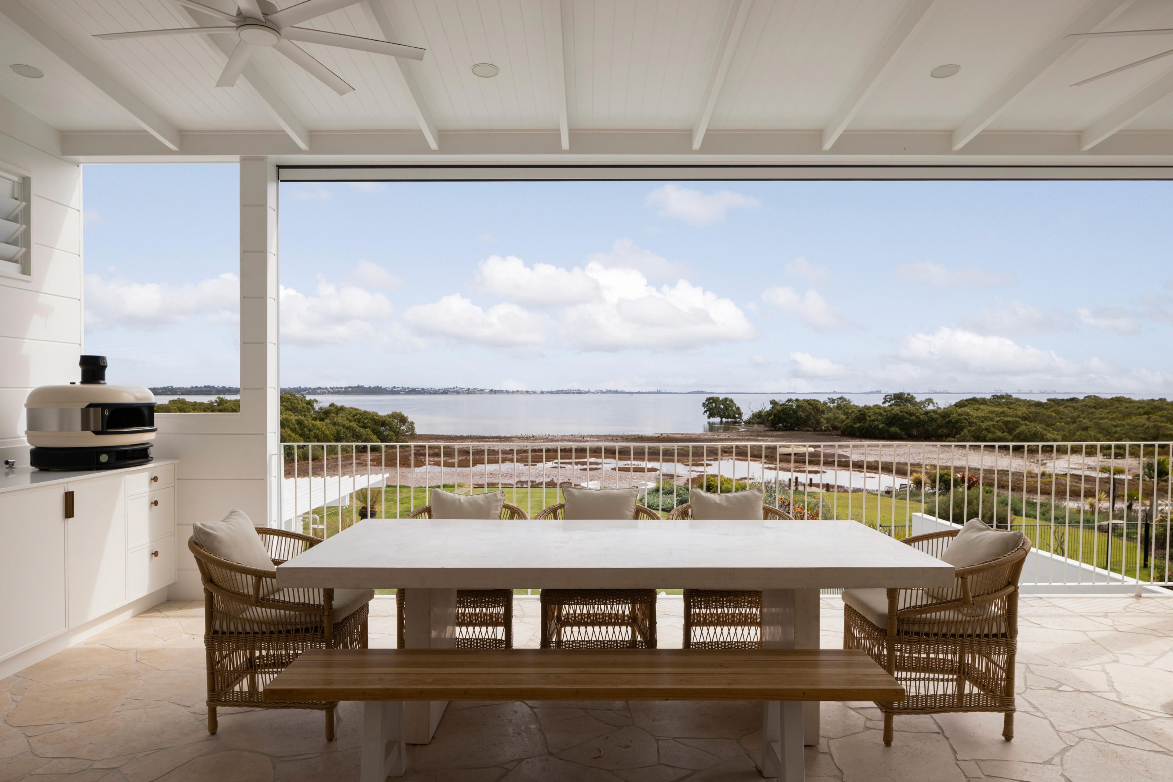 Covered outdoor dining terrace overlooking bay and pizza oven