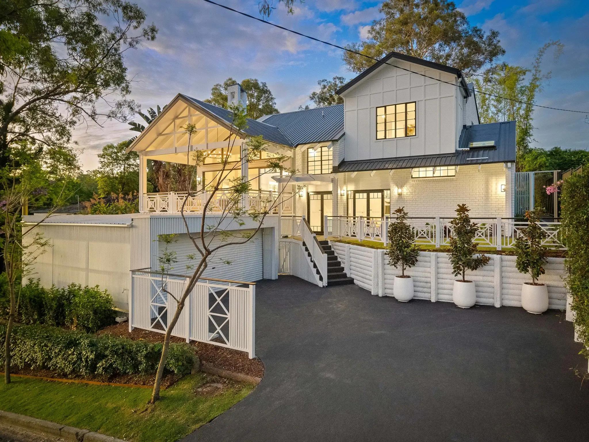 Two storey white home front exterior with driveway at dusk