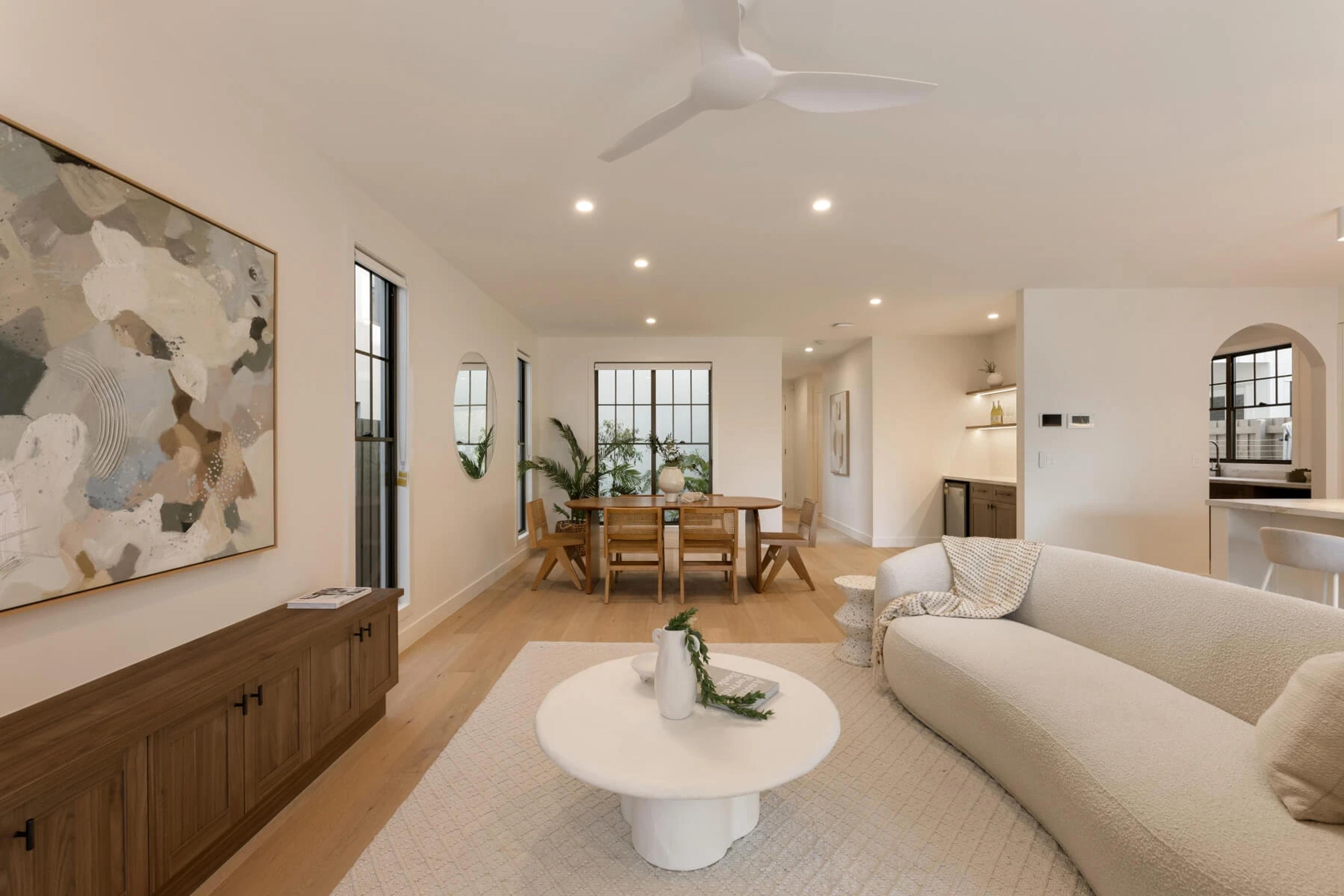 Living room with curved sofa, artwork and adjoining dining area