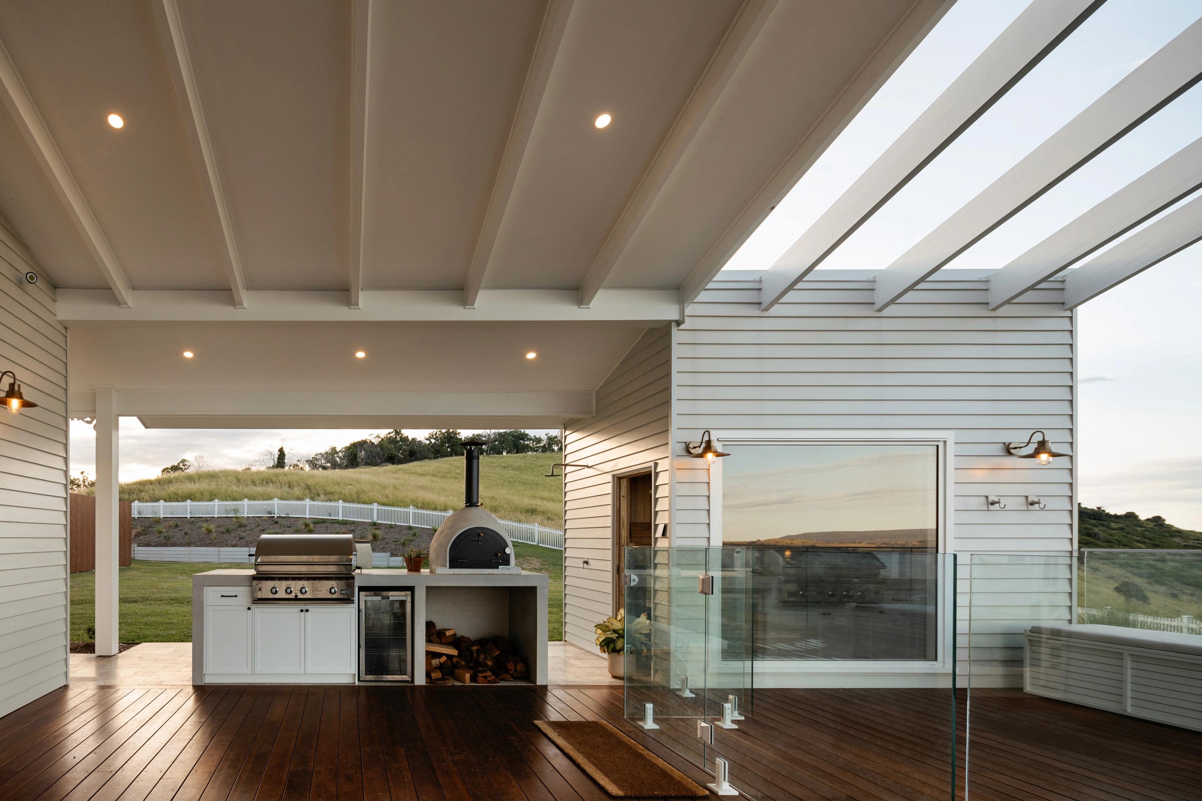 Outdoor kitchen with pizza oven and barbecue under covered deck