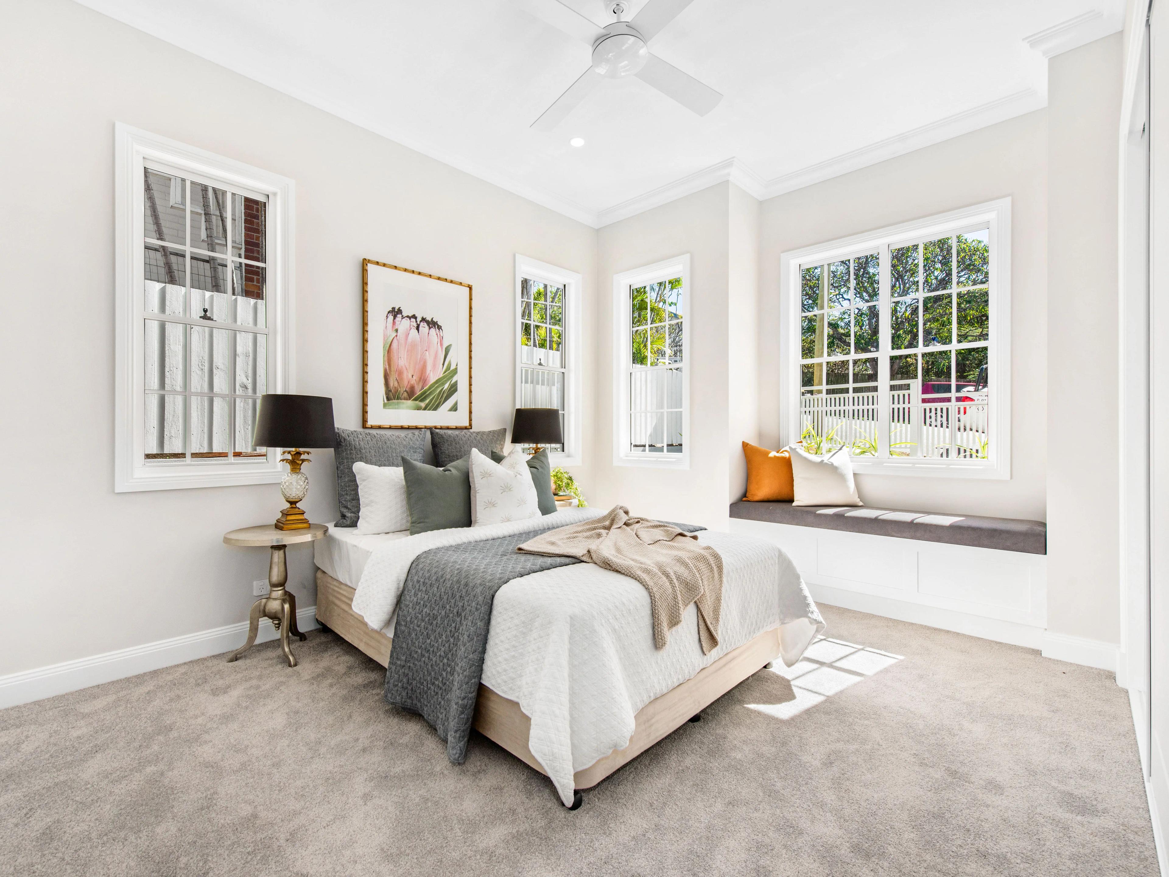 Bedroom with window seat and multiple white framed windows