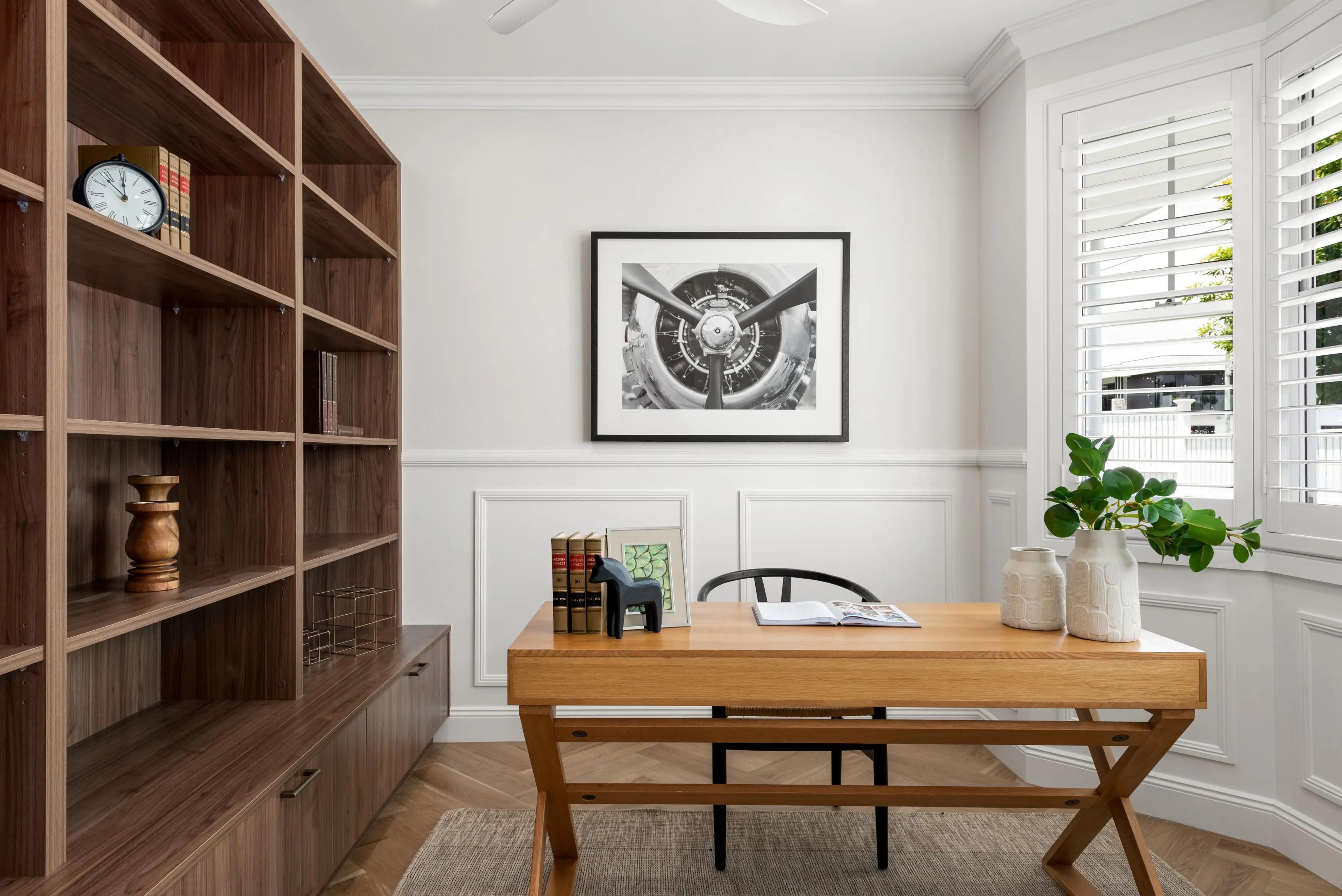 Home office with timber desk, bookshelves and plantation shutters