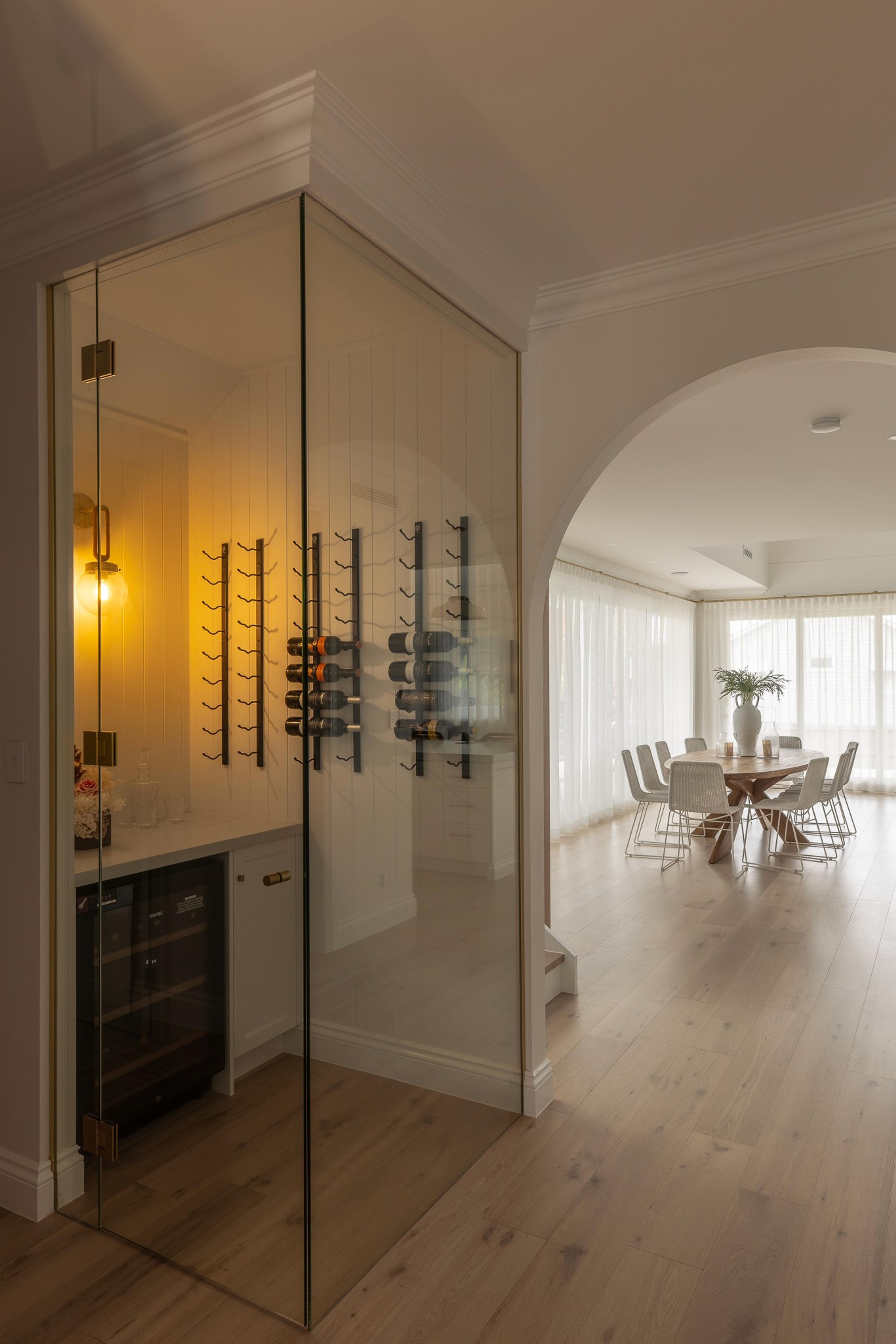 Glass walled wine cellar beside archway to dining room