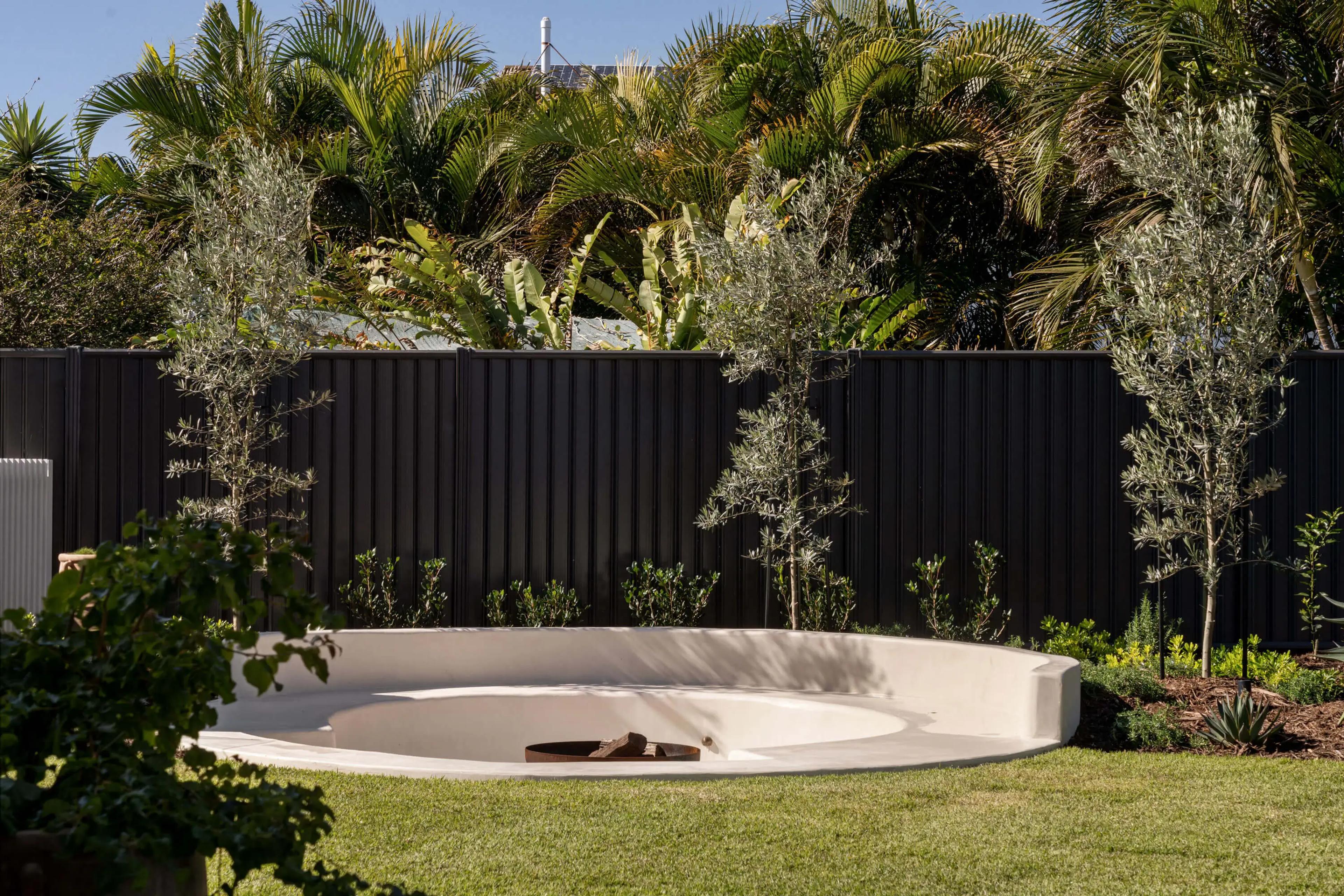 Rendered garden fire pit with olive trees and dark fence