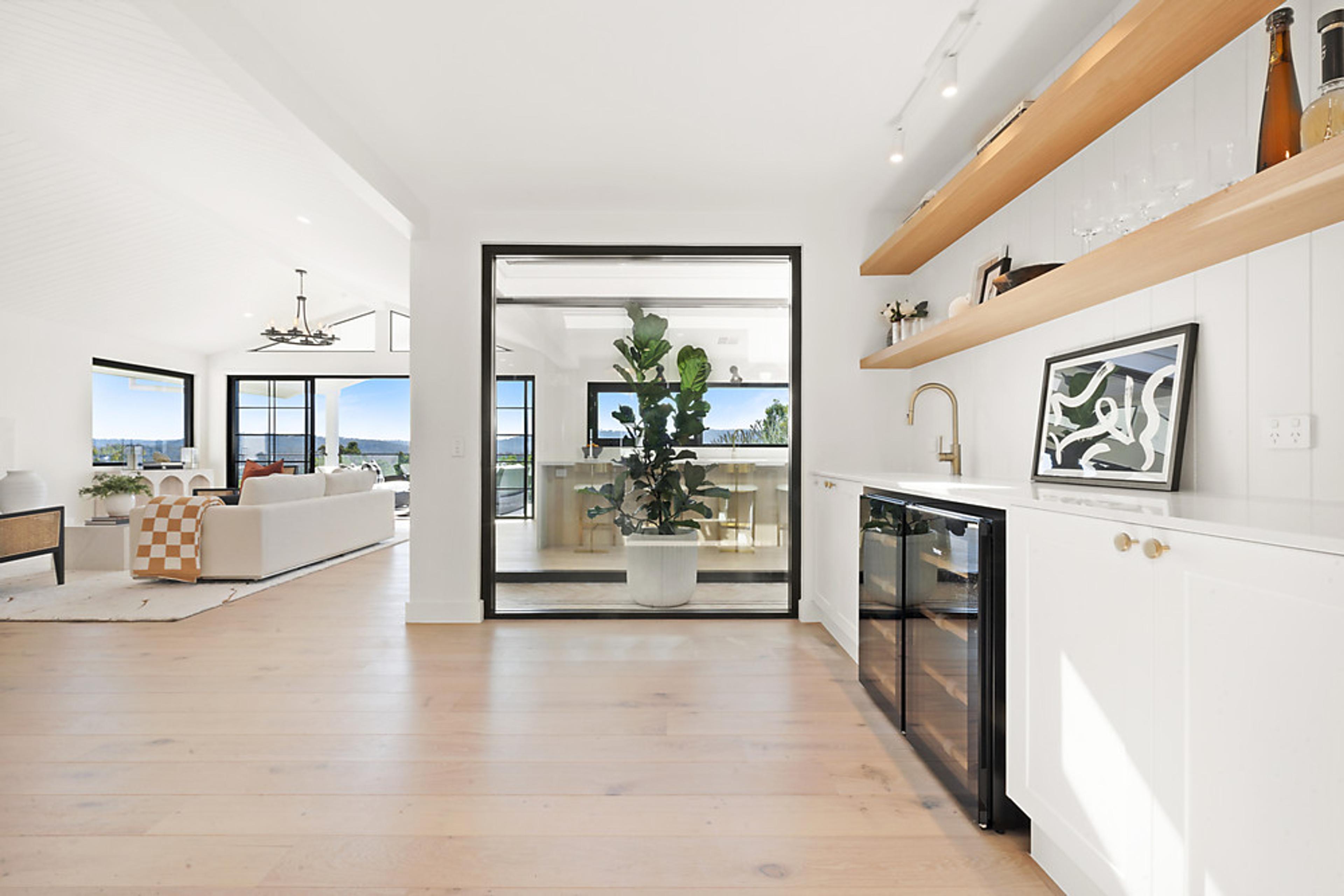Bar with wine fridge and timber shelving beside a glass window