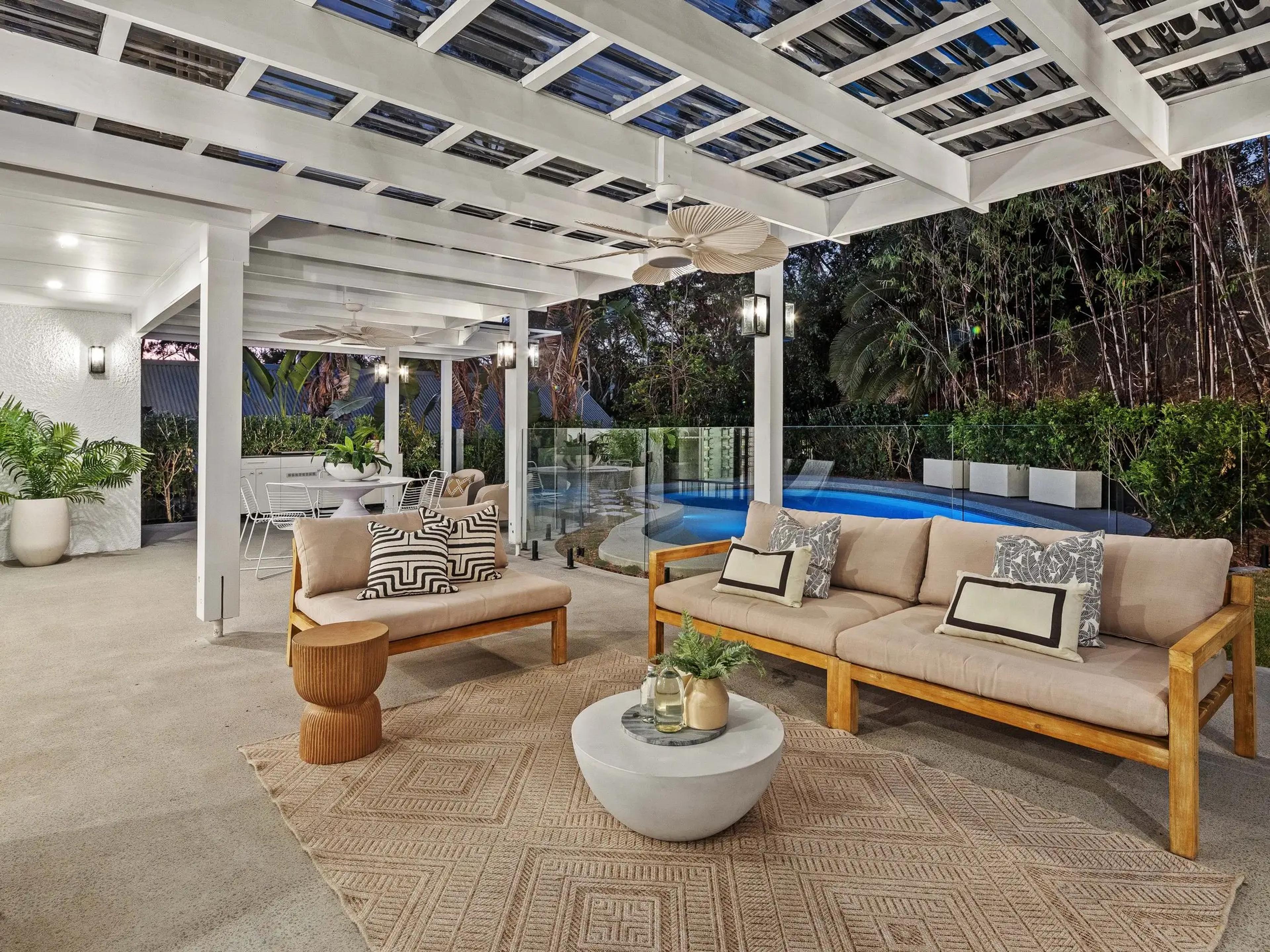 Outdoor lounge under pergola beside swimming pool