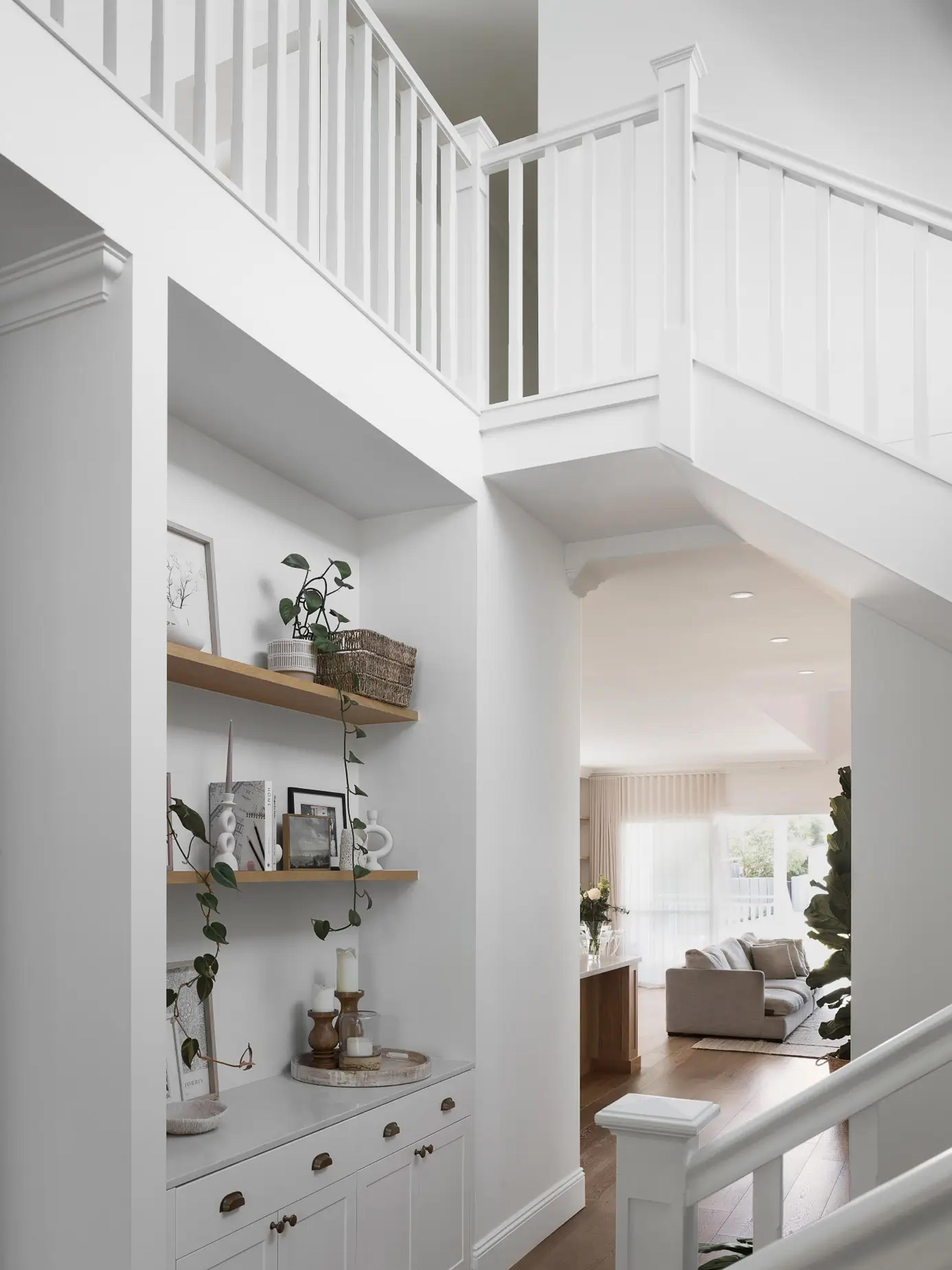 White staircase and built in shelving beside a bright living room
