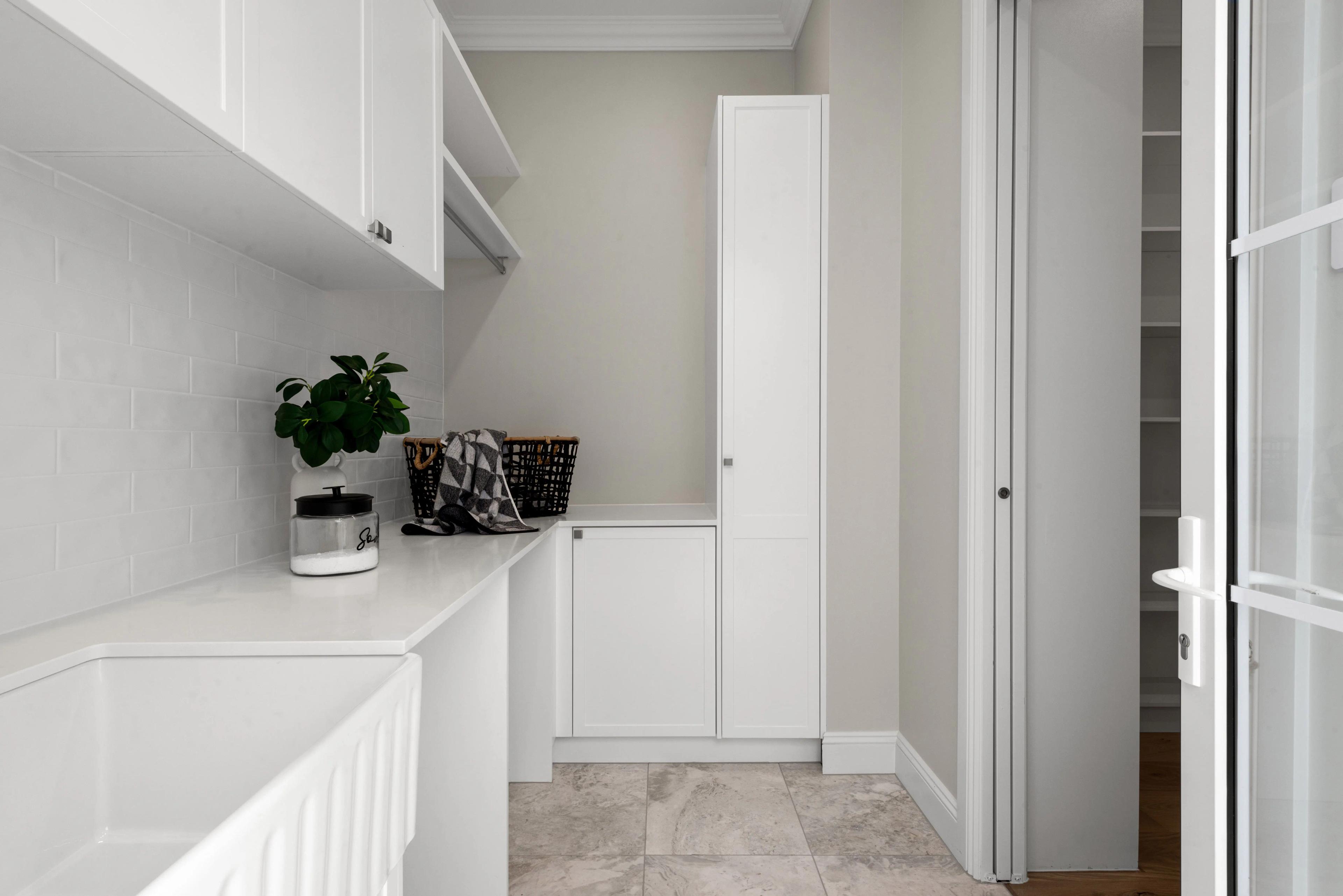 White laundry with cabinetry and tiled flooring