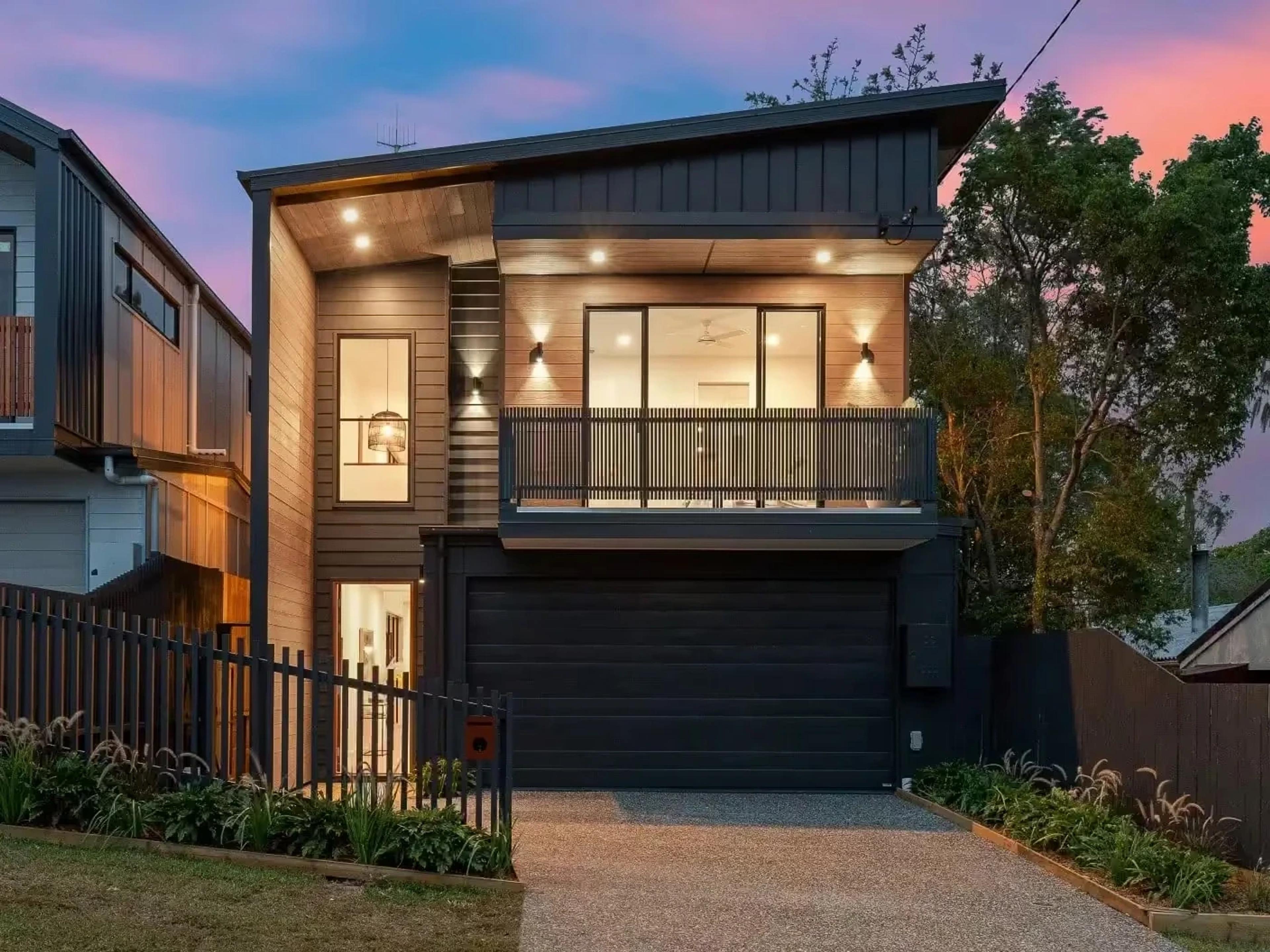 Two storey timber and dark clad home facade at dusk