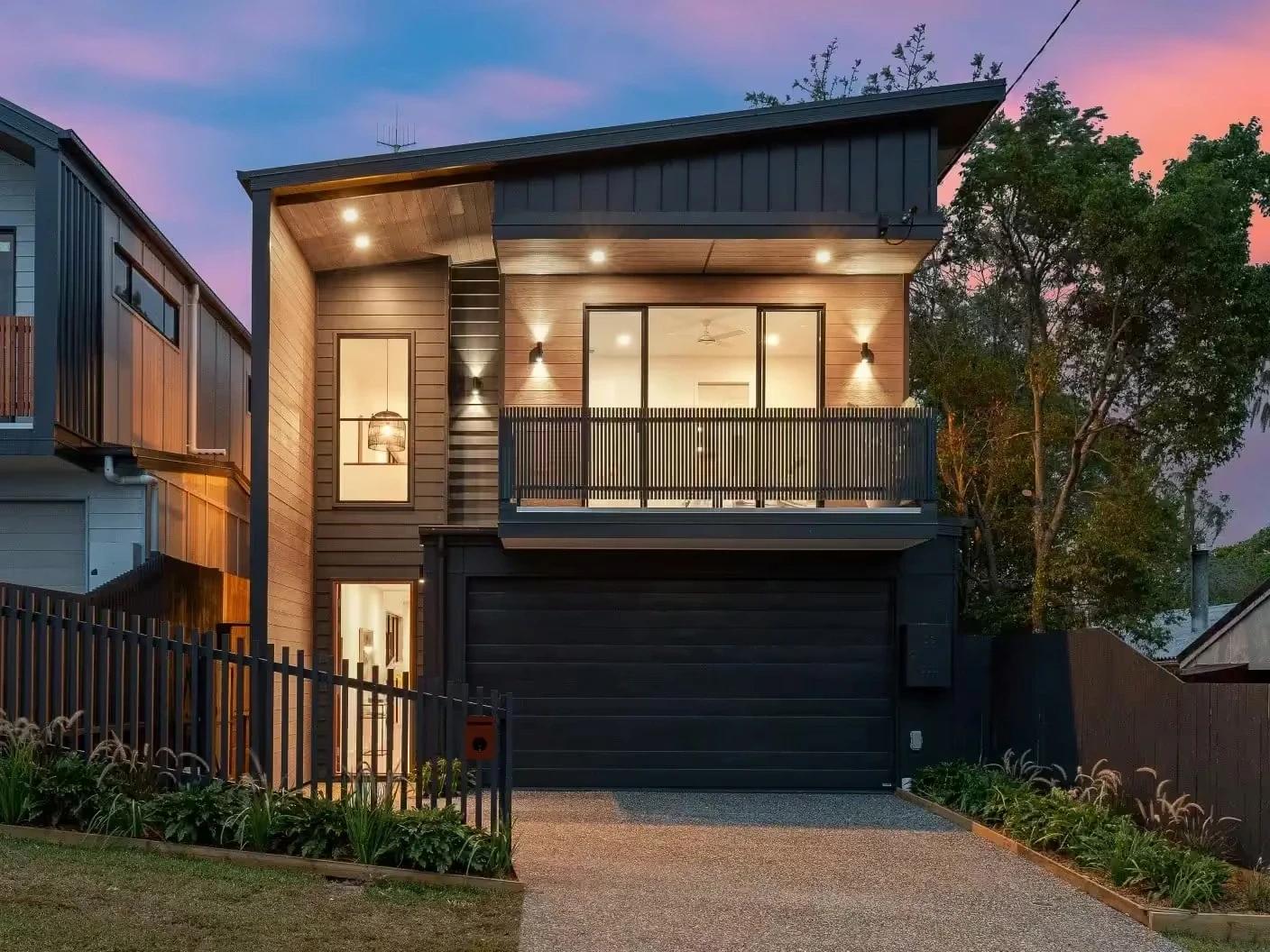 Two storey timber and dark clad home facade at dusk