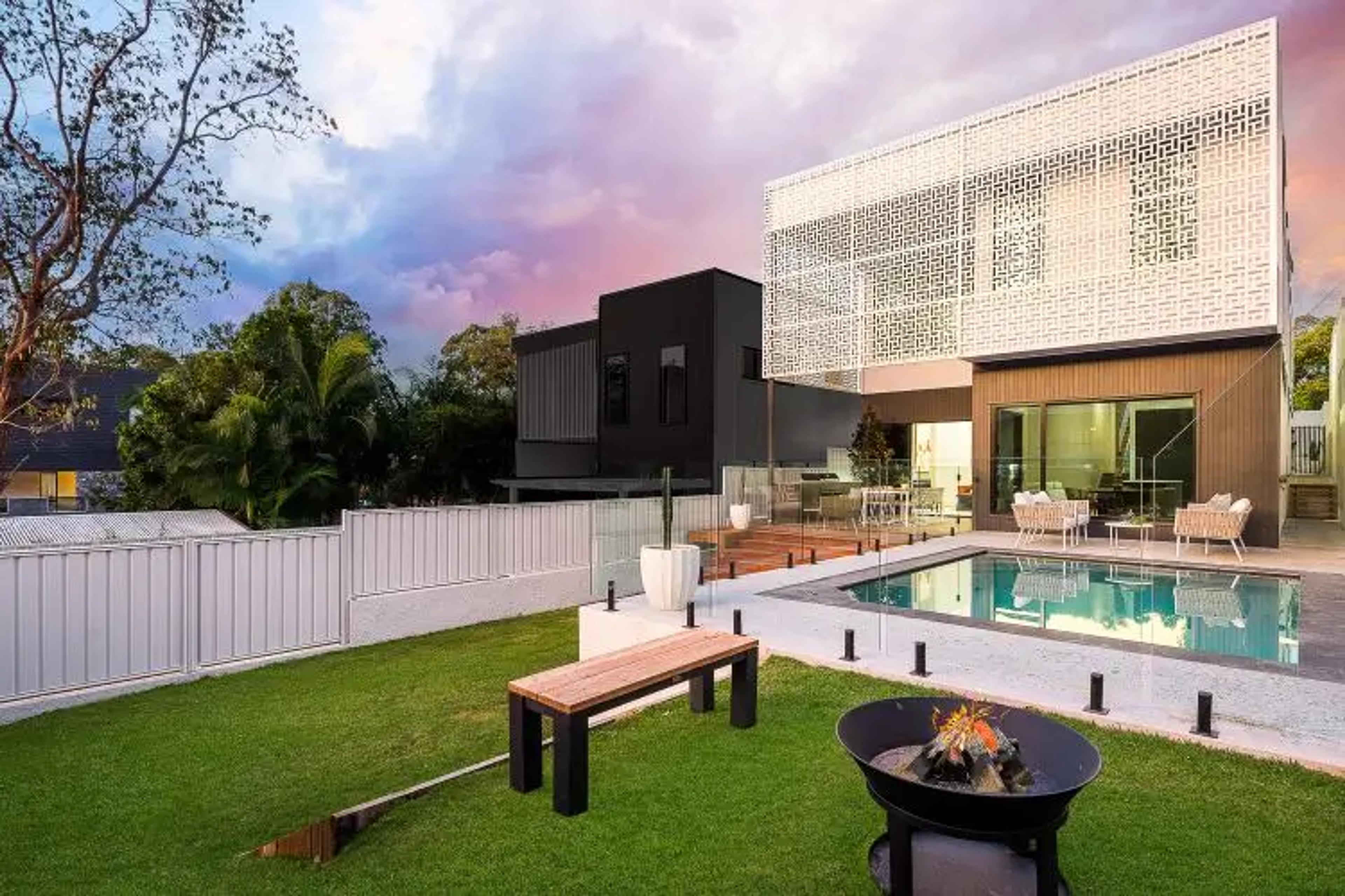 Rear exterior with pool, lawn and fire pit at dusk