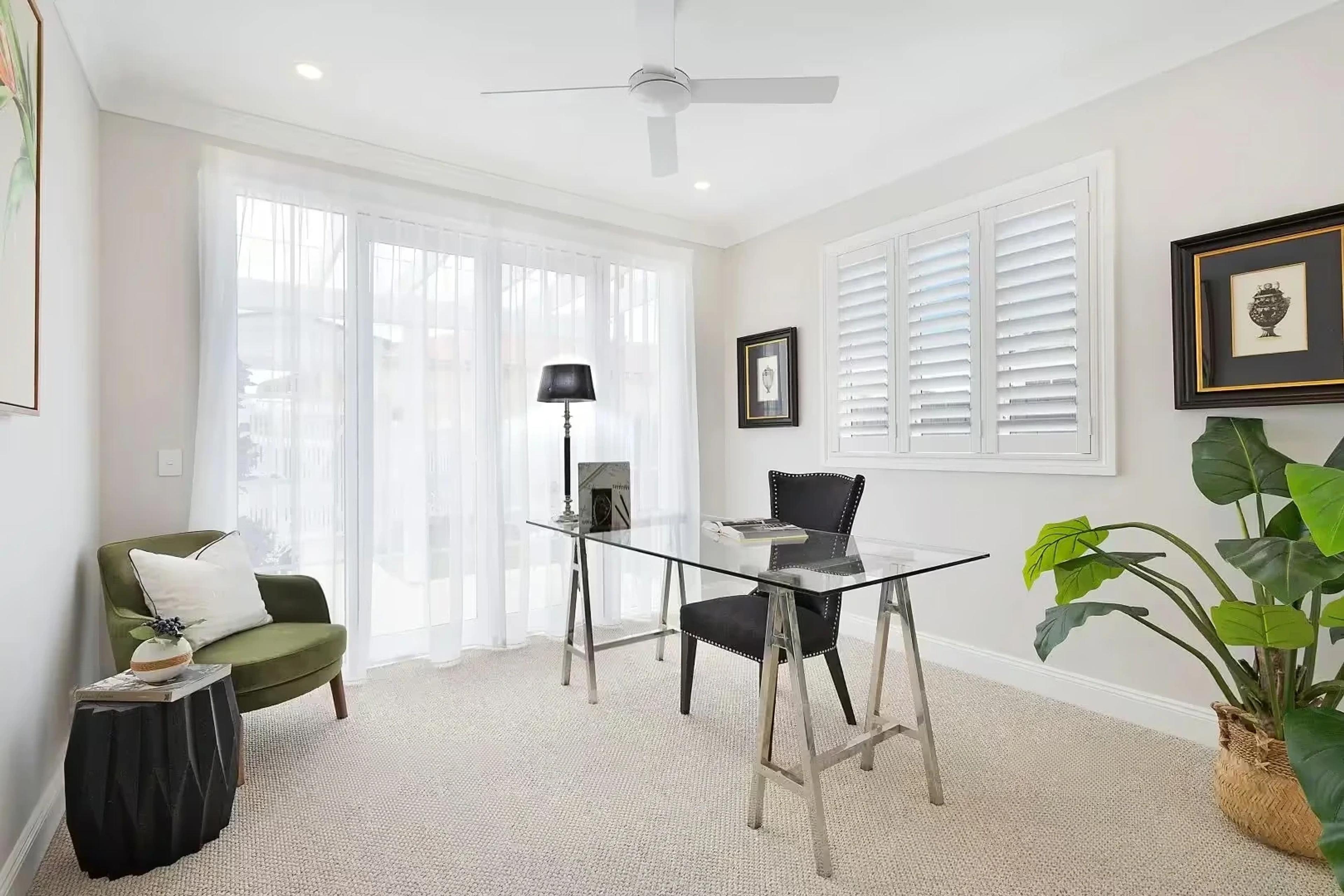 Home office with glass desk and plantation shutters