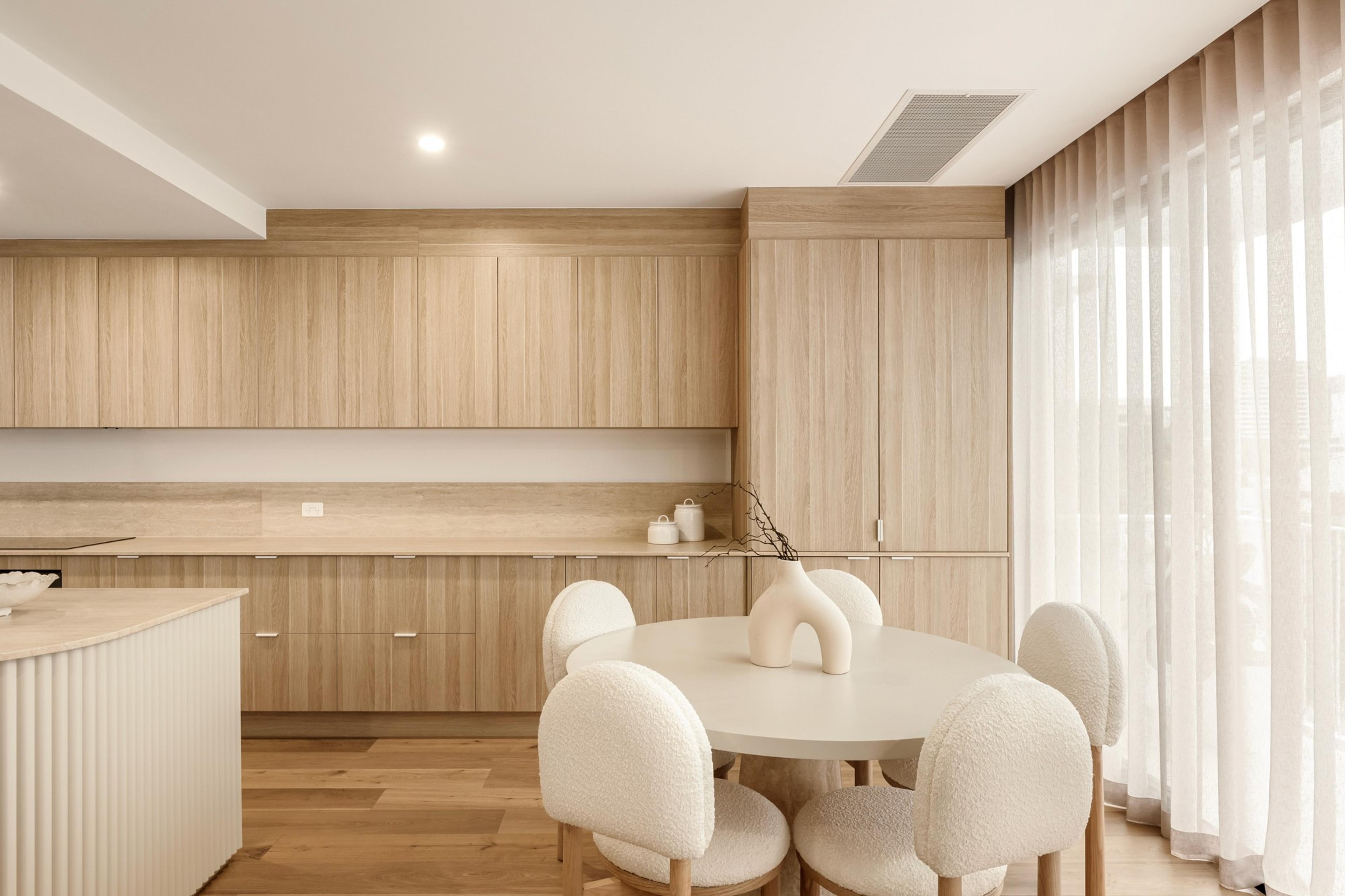 Dining area with round table, timber joinery and sheer curtains