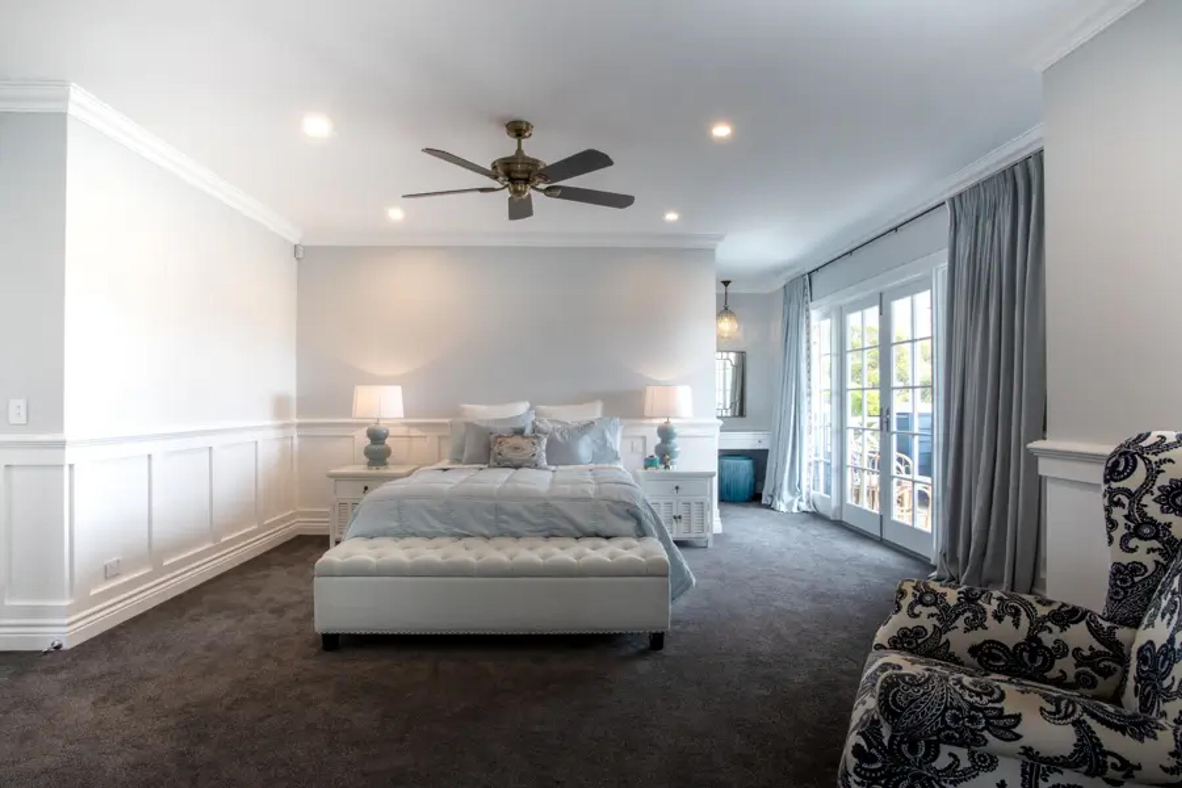 Main bedroom with ceiling fan and balcony doors