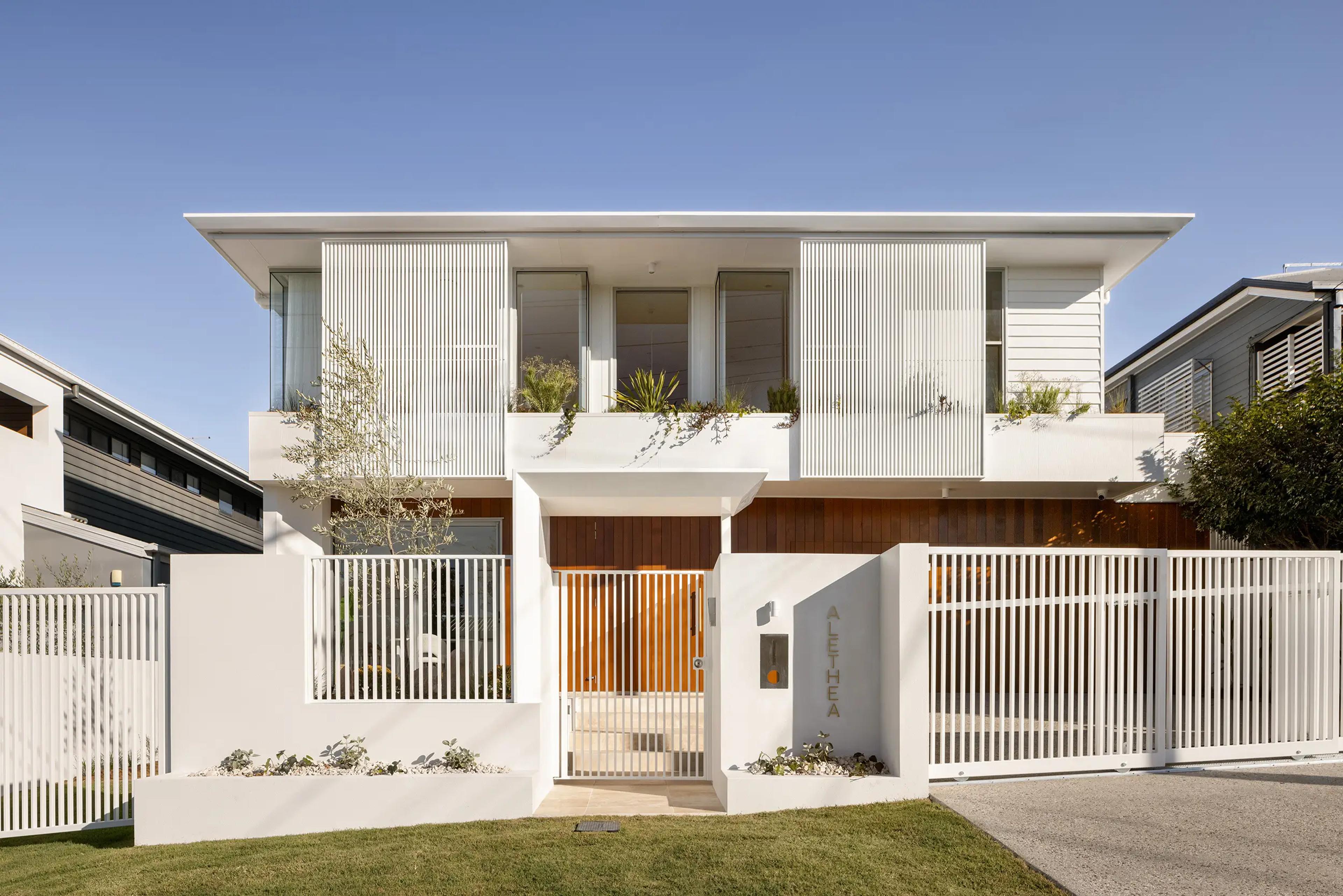 Two storey white home facade with slatted fence and gate