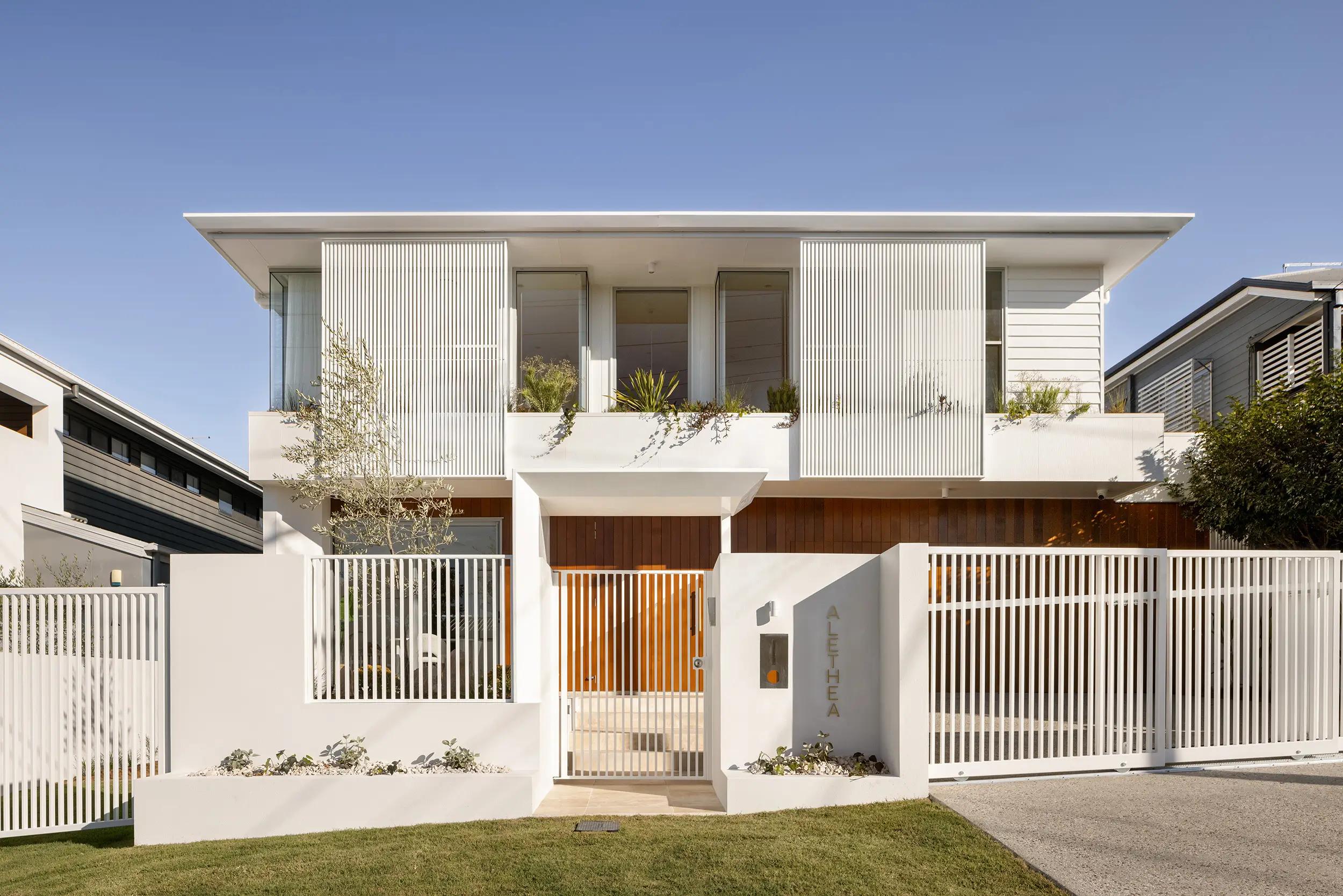 Two storey white home facade with slatted fence and gate