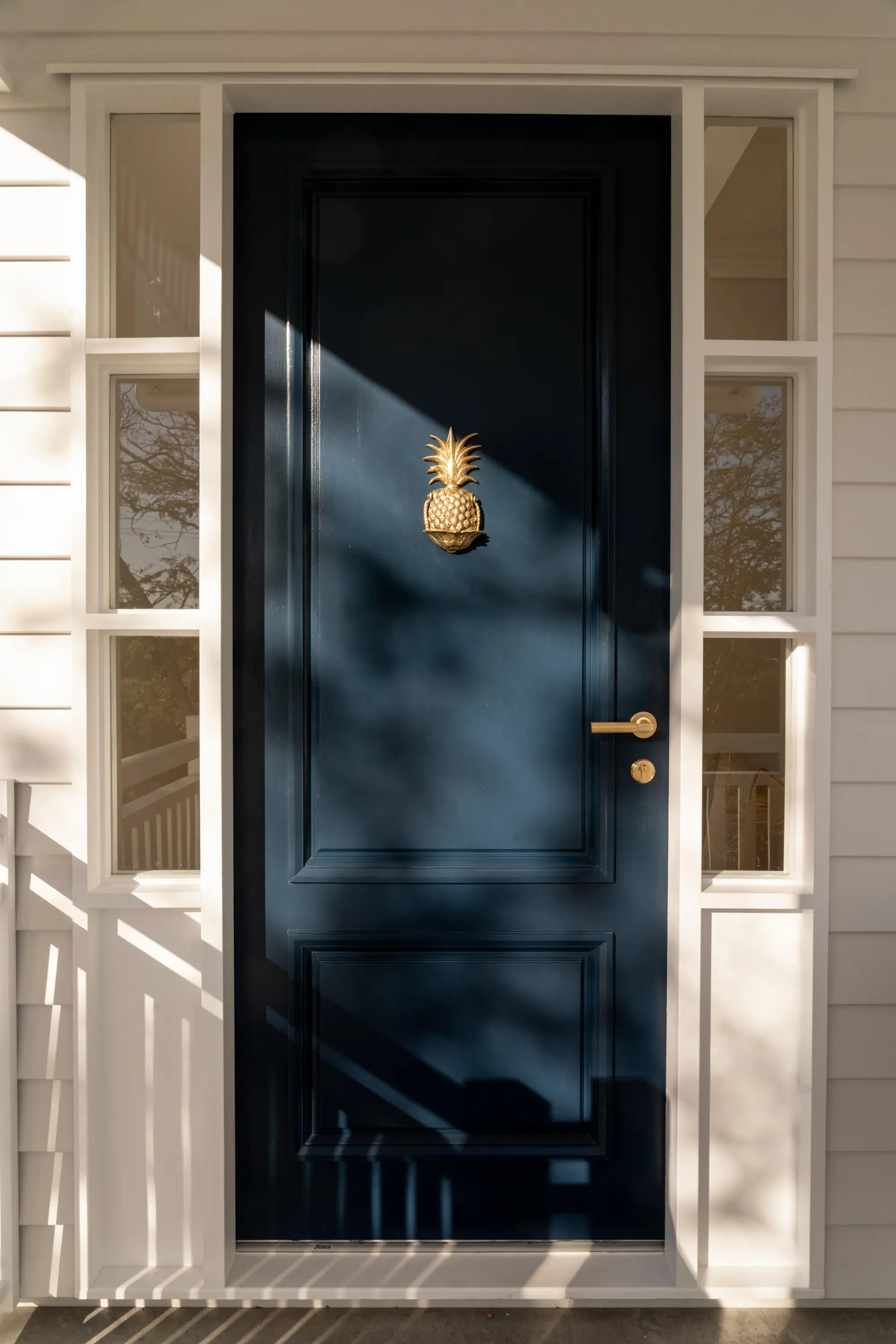 Navy front door with brass pineapple knocker and side windows