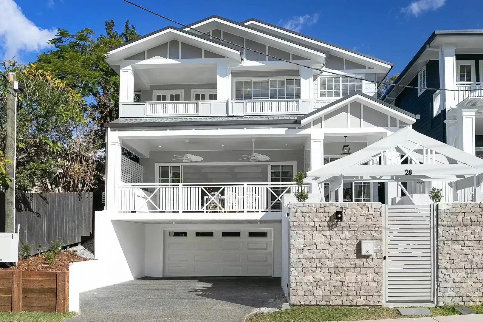 White two storey Hamptons style home with double garage and stone fence