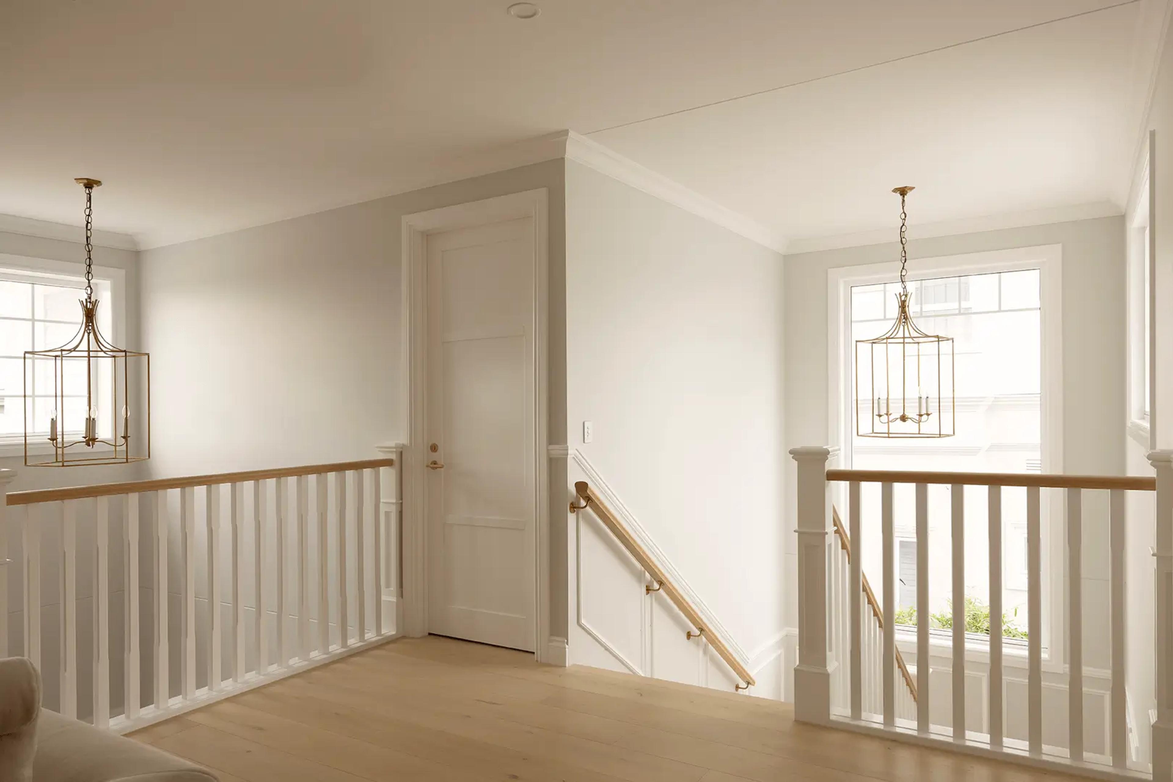 Upstairs landing with white balustrade and lantern pendants
