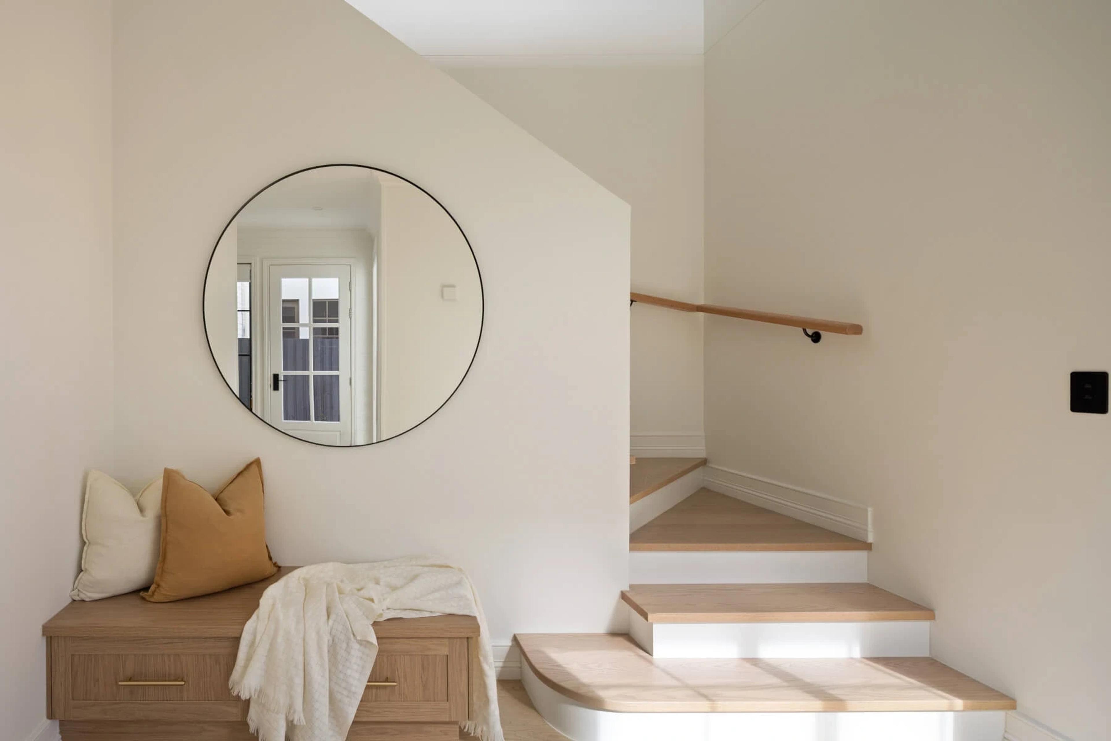 Landing with round mirror, storage bench and timber staircase