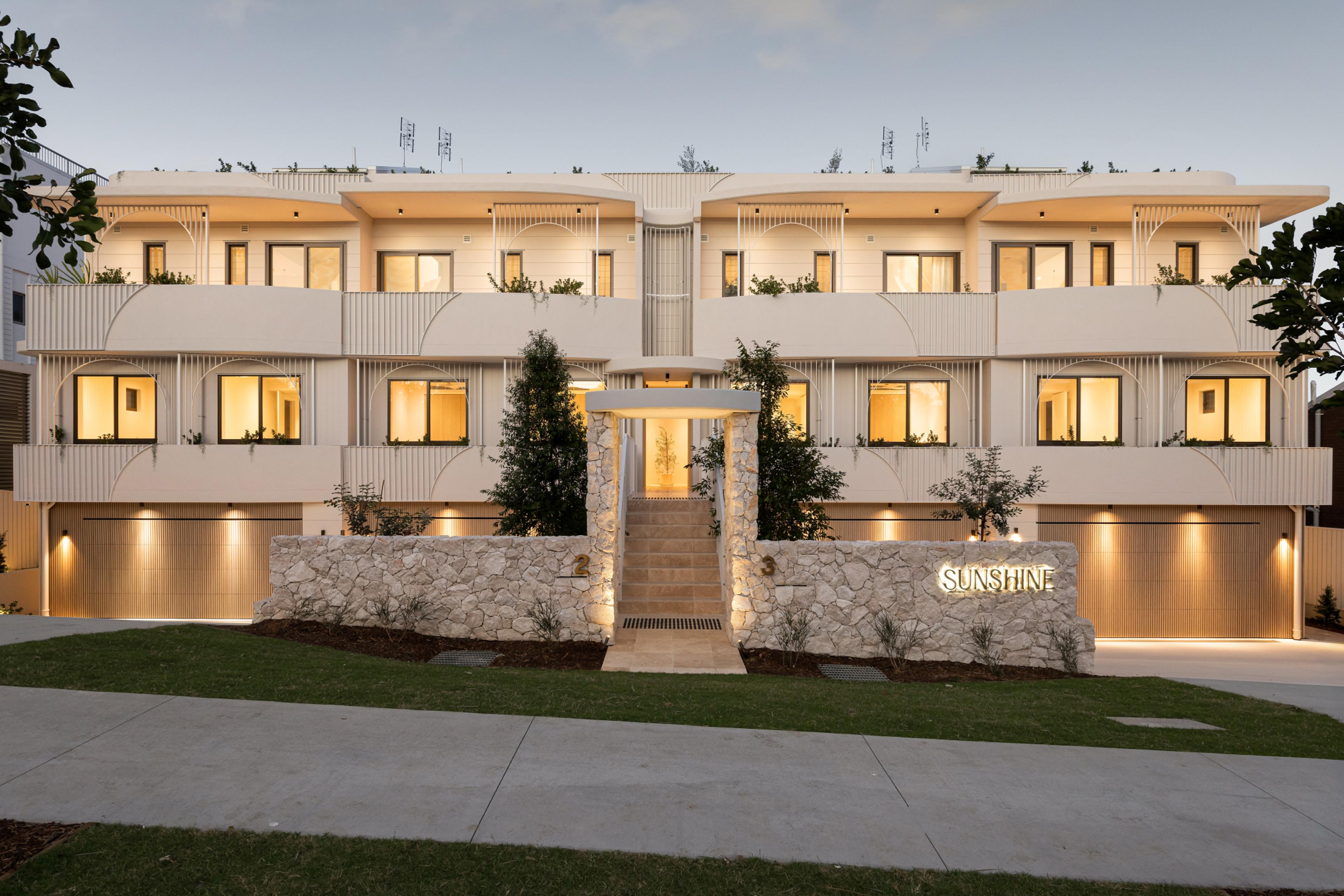 Sunshine, a residential development at Sunshine Beach designed by Invilla Architecture, dusk street view with arched balconies and stone entry