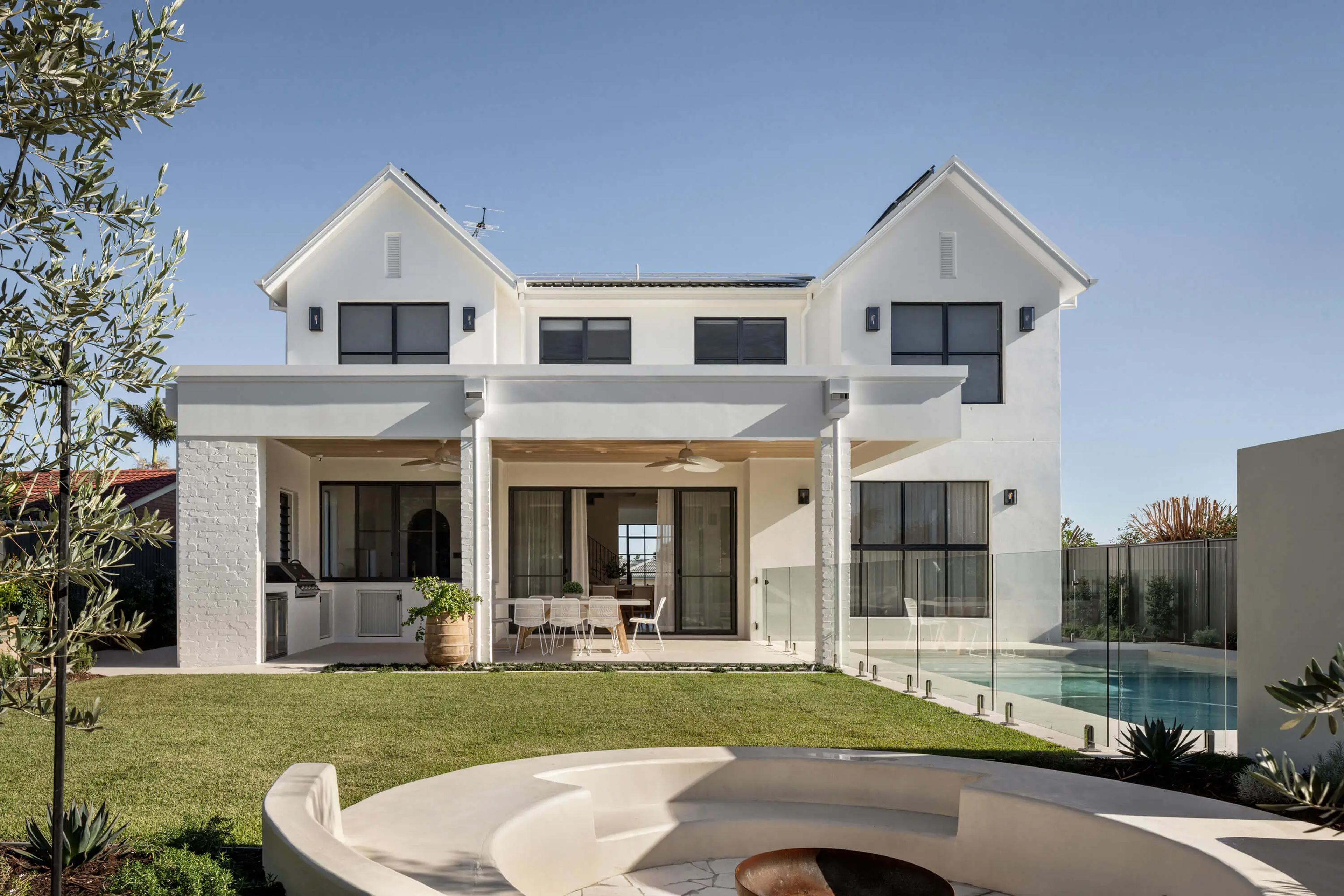 Rear elevation of white gabled home with pool and lawn