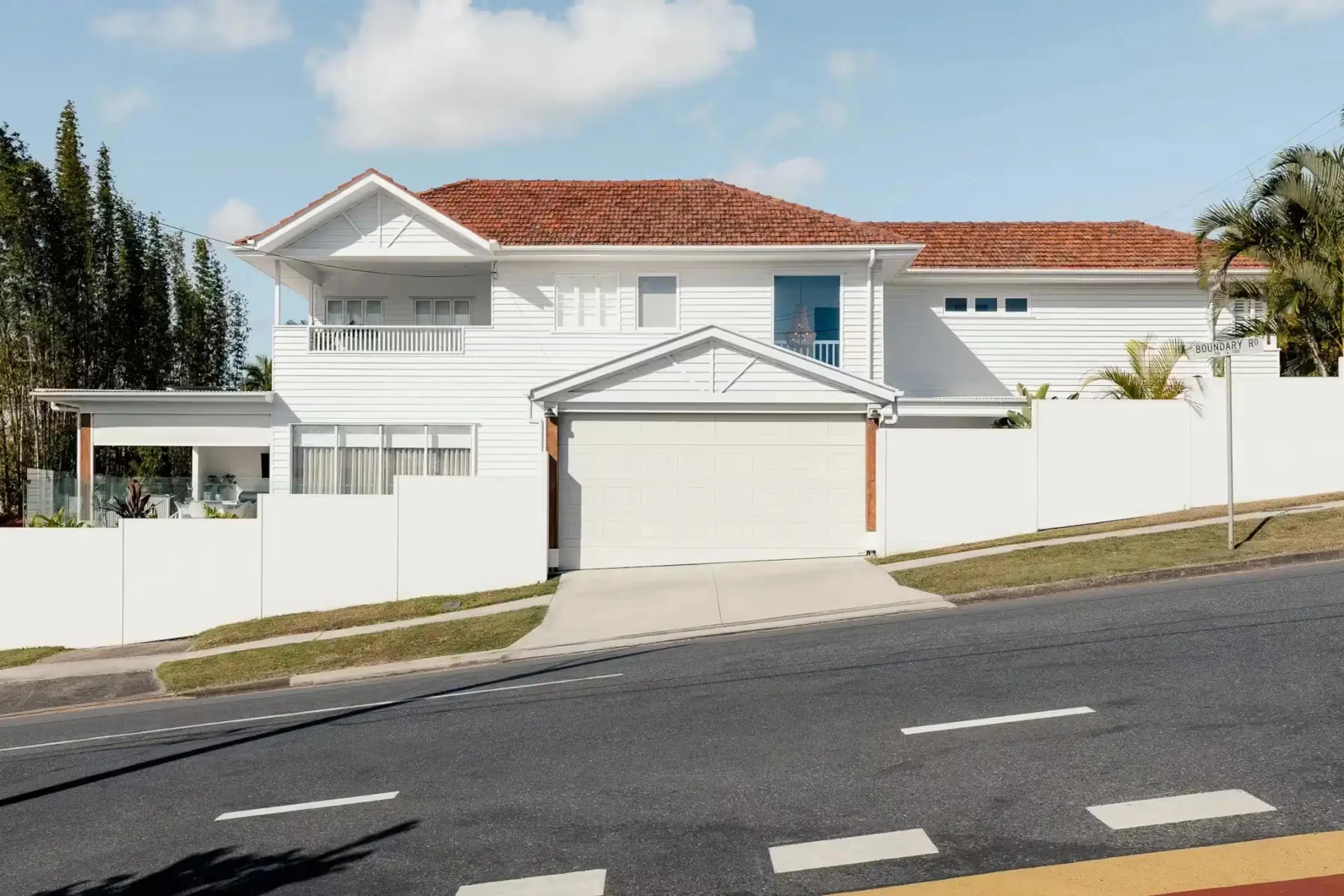 Two storey white weatherboard home with garage from street