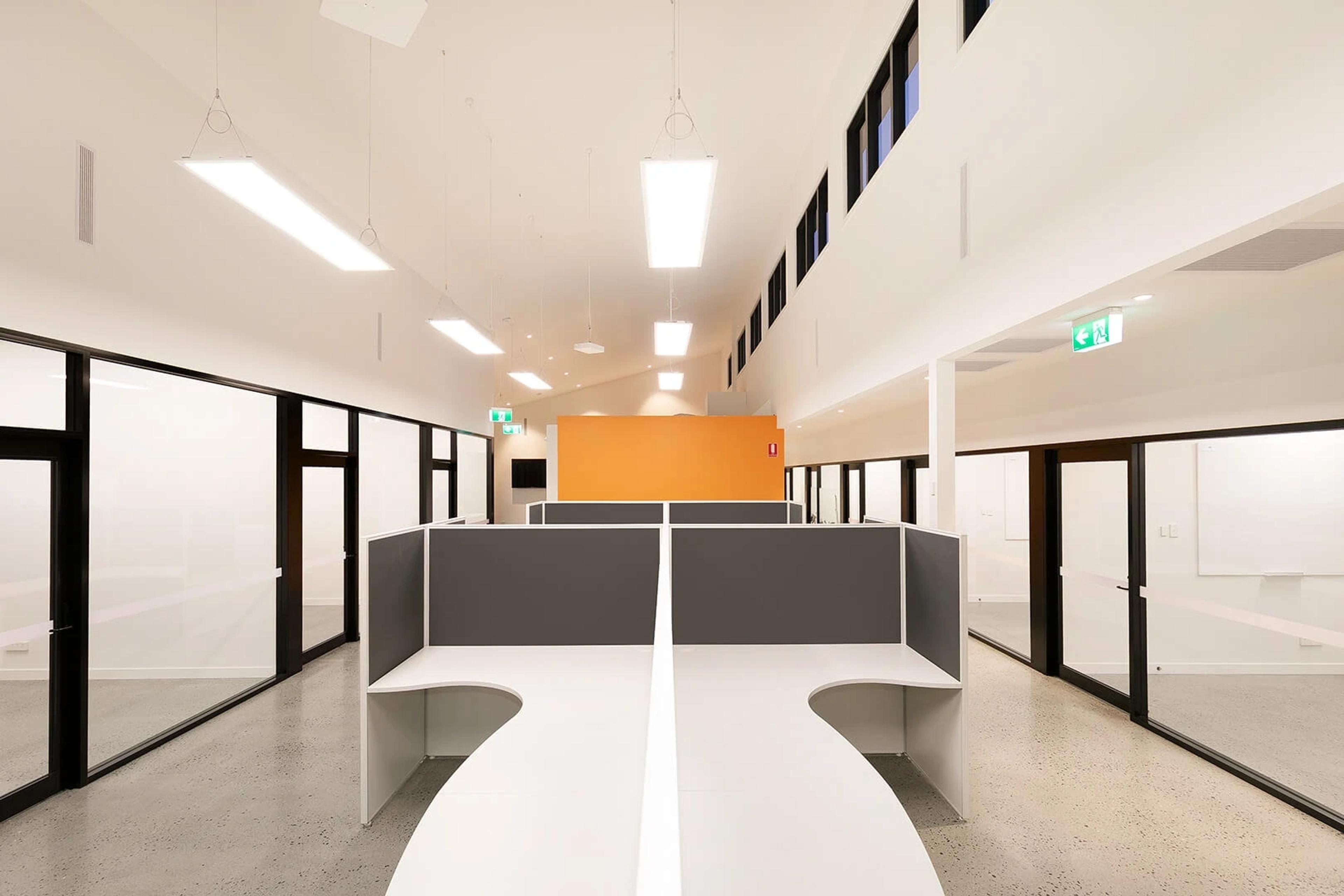 Symmetrical office cubicles with orange accent wall beyond