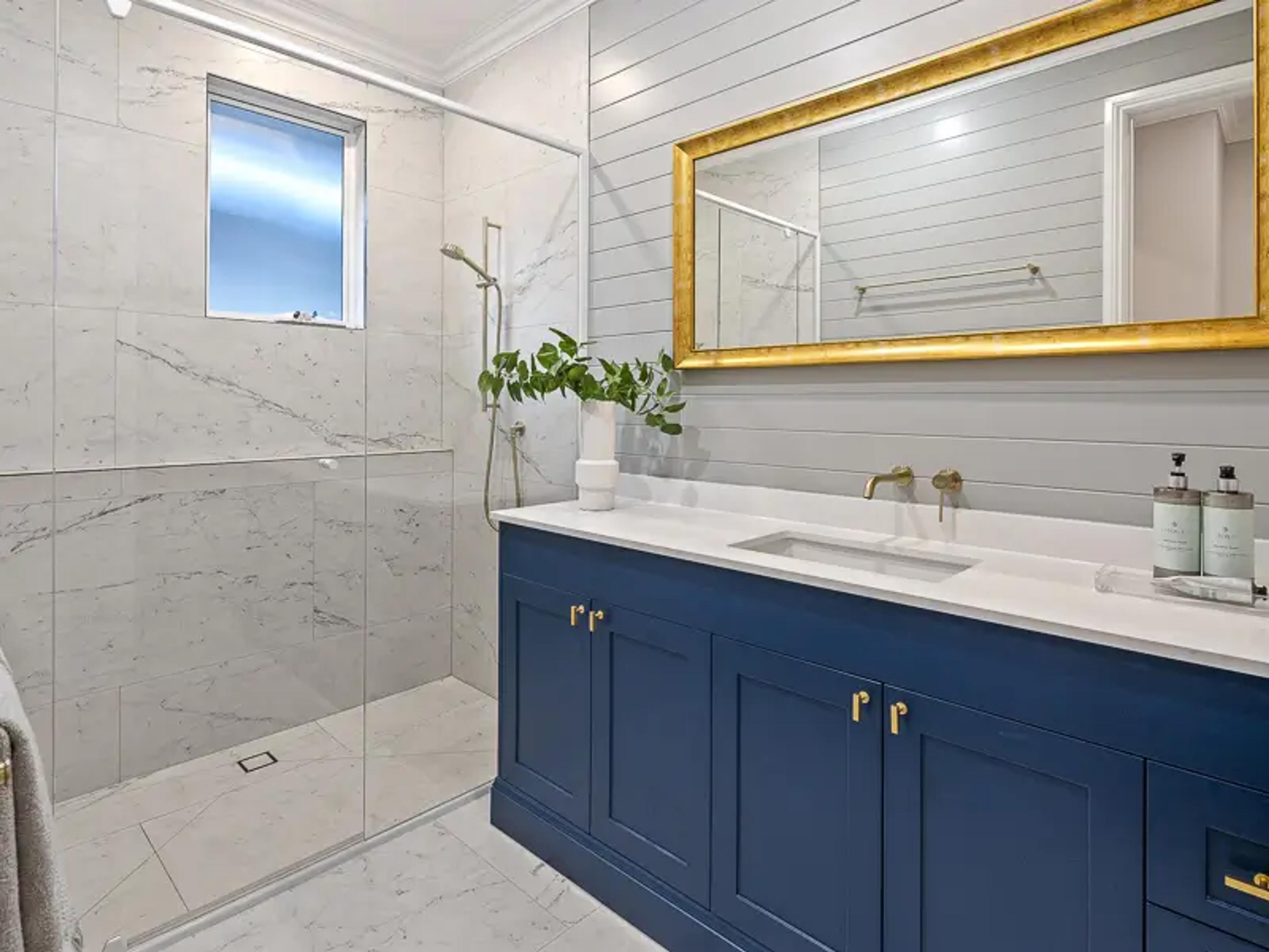 Bathroom with blue vanity, walk in shower and marble tiles