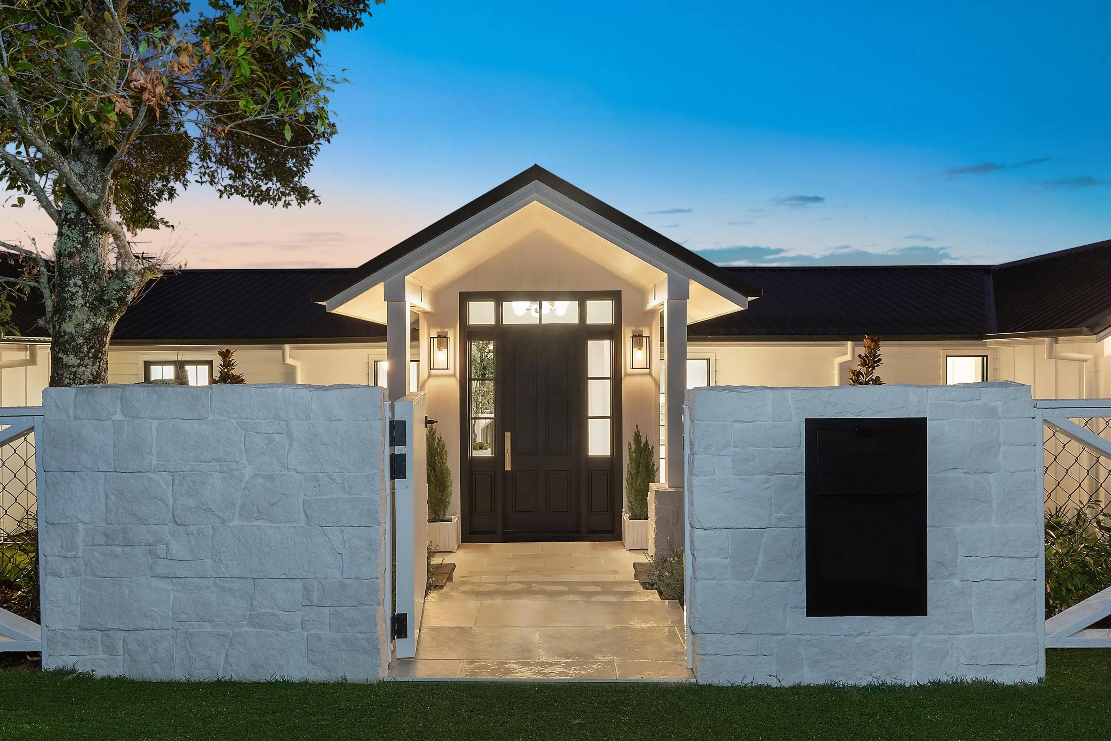 Front entrance at dusk with stone gate walls and portico.