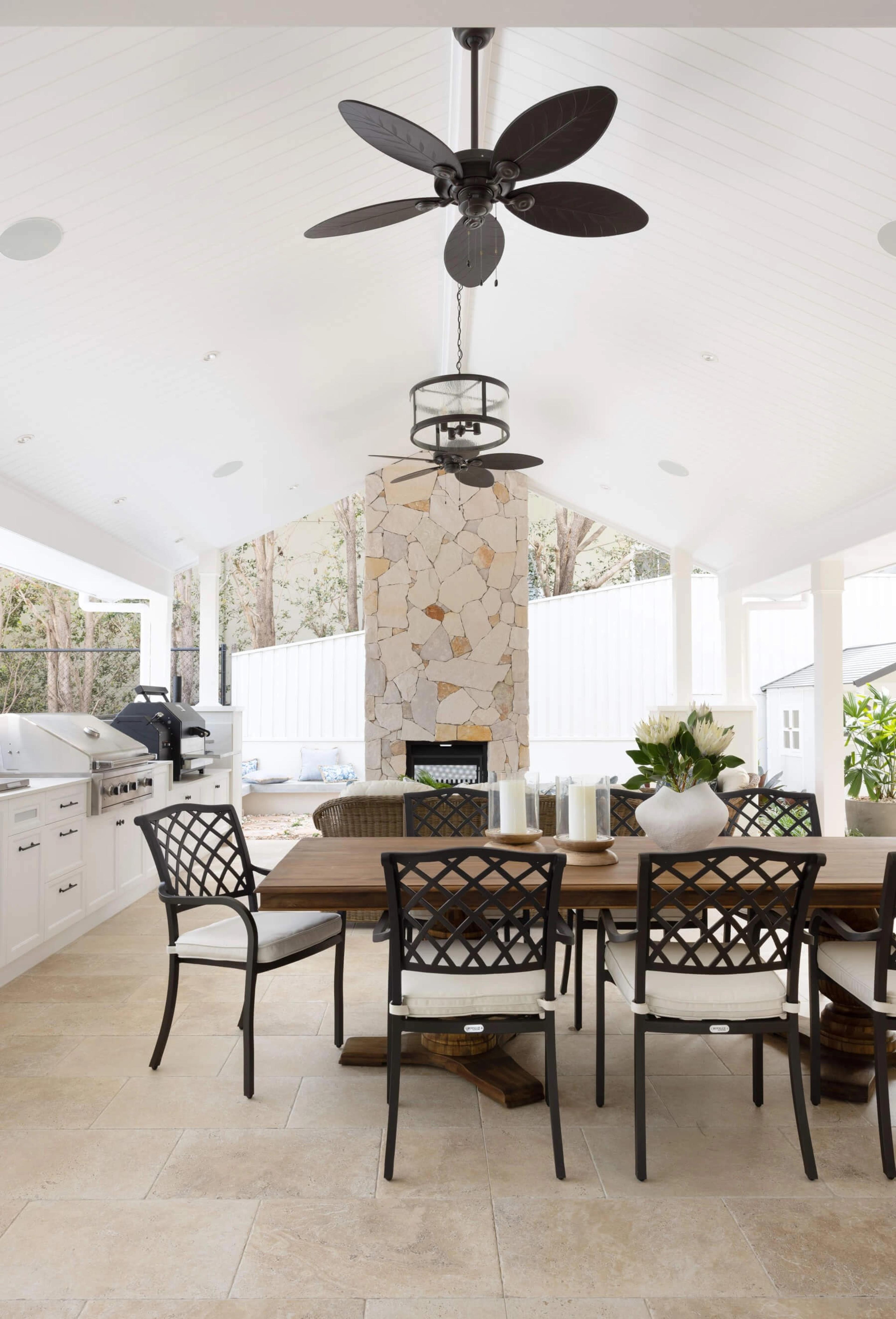 Covered outdoor dining area with stone fireplace and barbecue