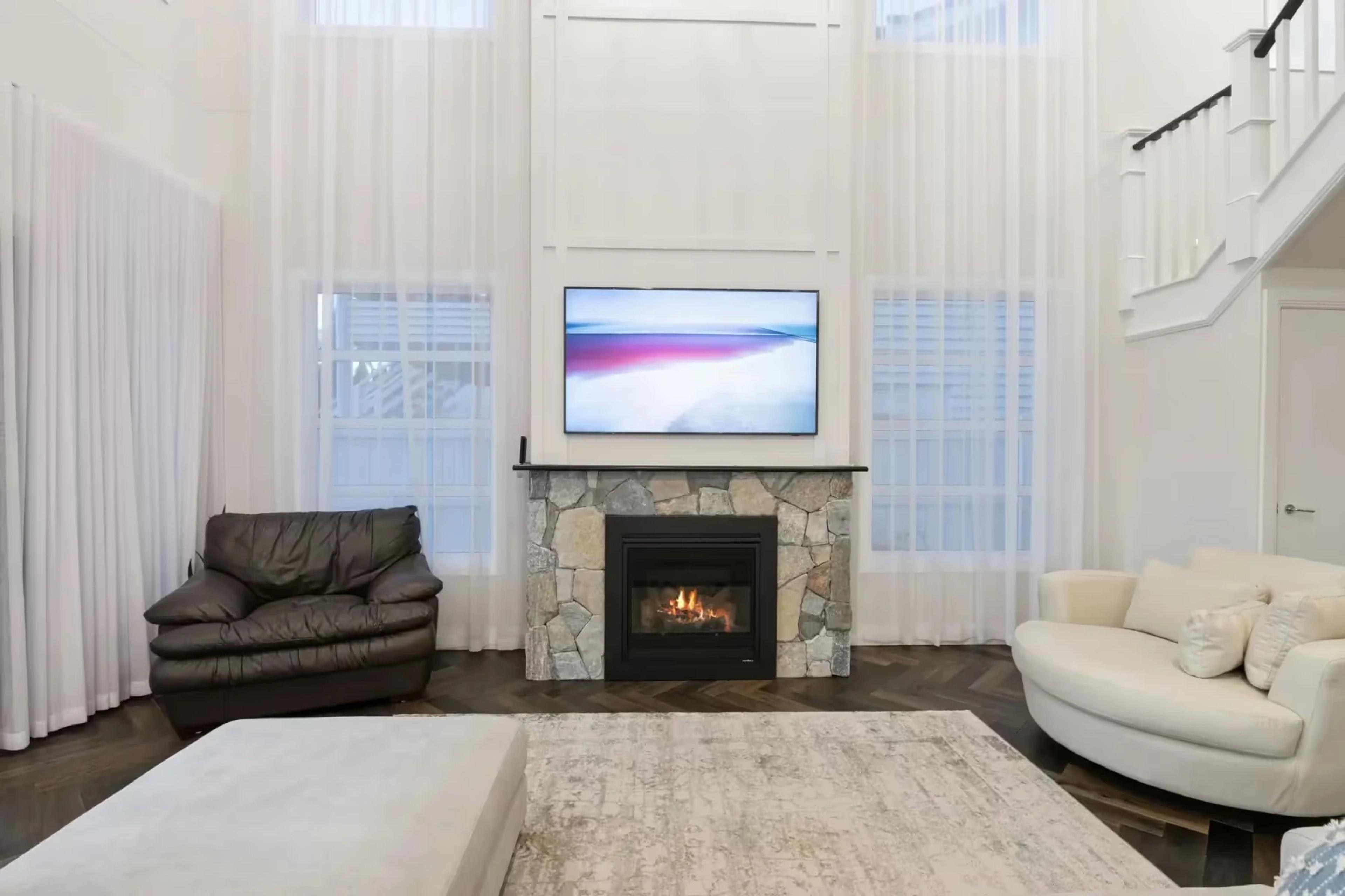 Double height lounge with stone fireplace and sheer curtains