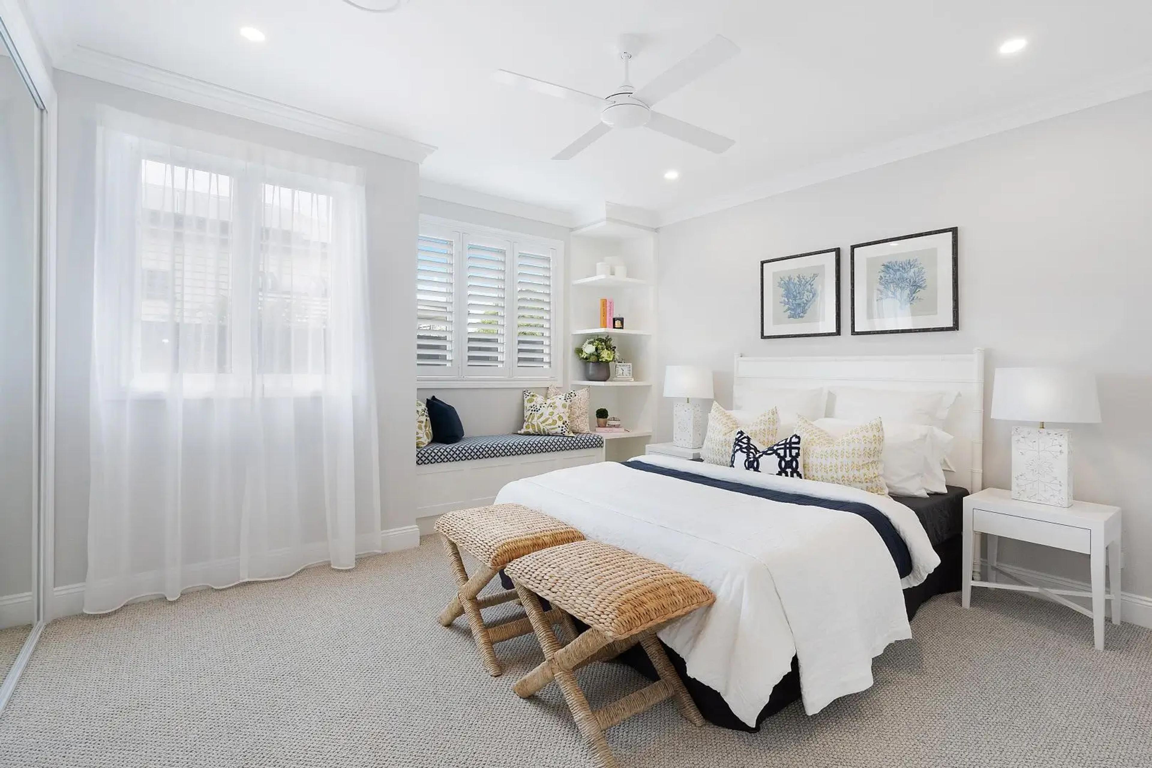 Bedroom with window seat and framed prints above bed