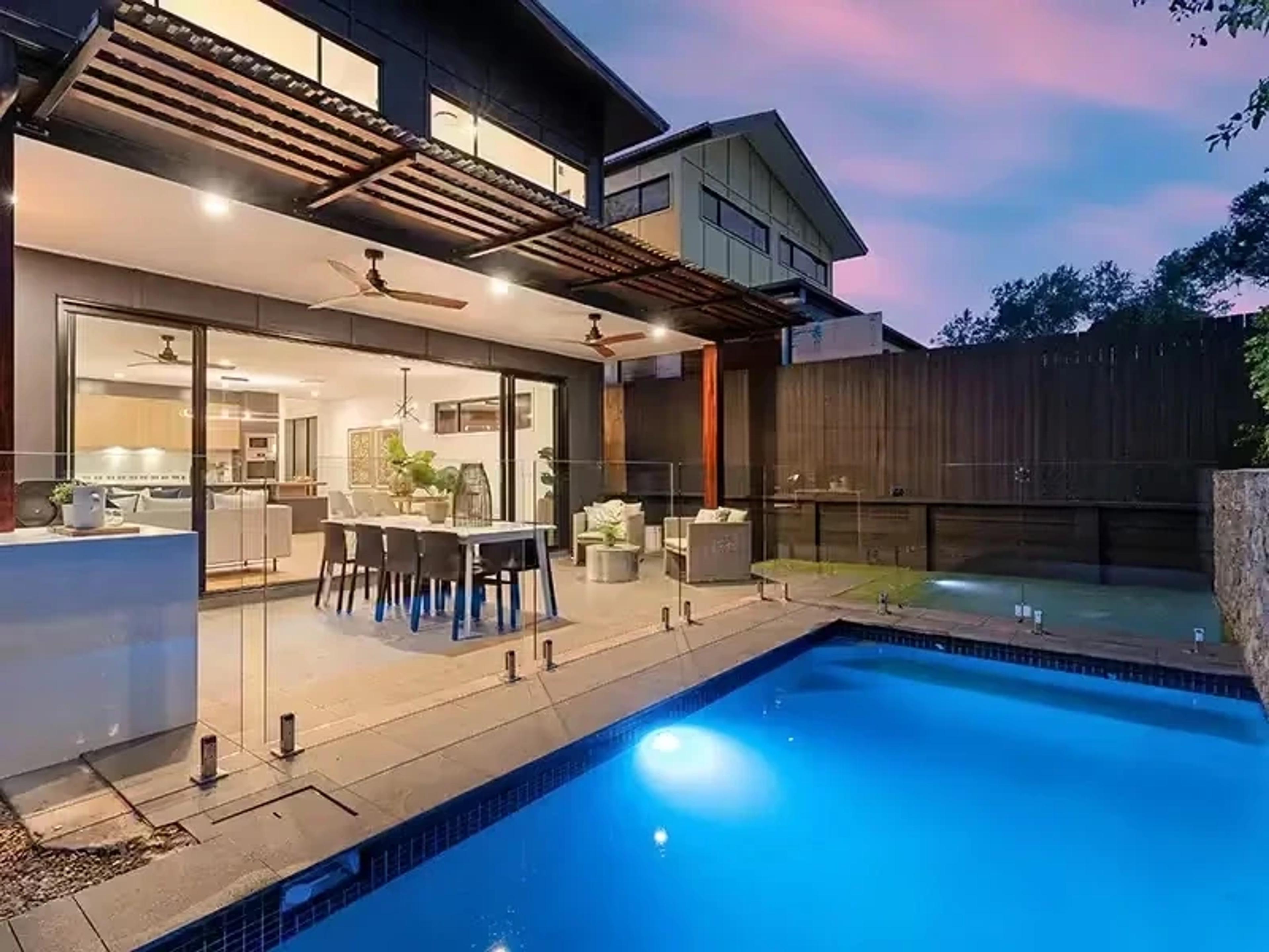 Rear of home with pool, patio and timber pergola at dusk